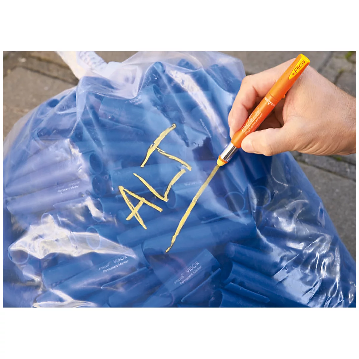 A hand writes the word "ALT" with an orange pen on a blue bag.