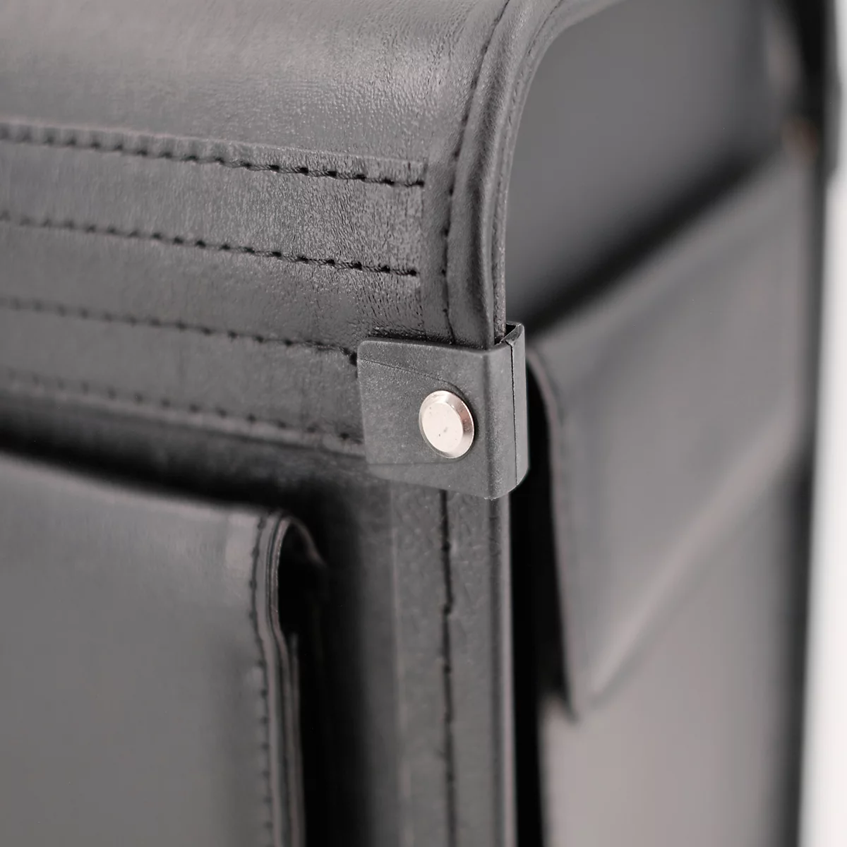 Detailopname van een zwarte leren tas met een zilveren knoopsluiting.