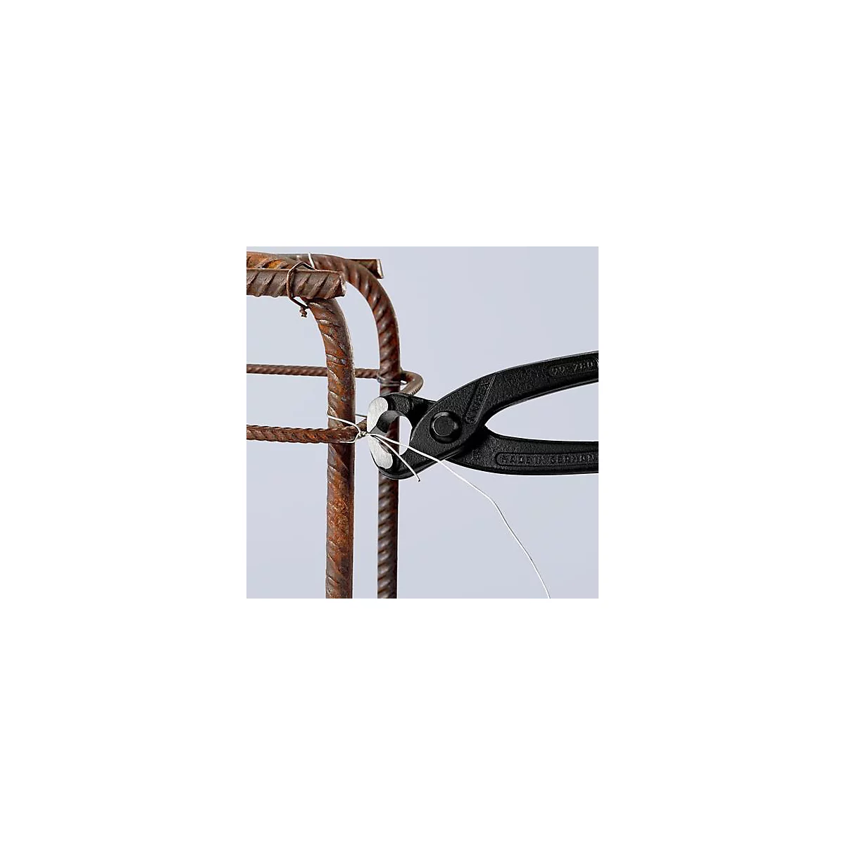 Une pince noire attache du fil de fer autour d'acier d'armature, avec une armature en acier en arrière-plan.