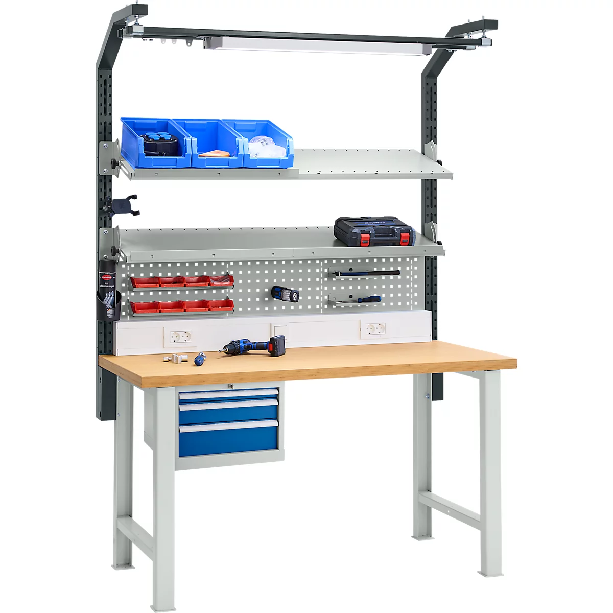Établi avec éclairage, étagères, tiroirs et panneau perforé, équipé d'outils. Des vis et une visseuse sans fil sont sur la surface de travail.