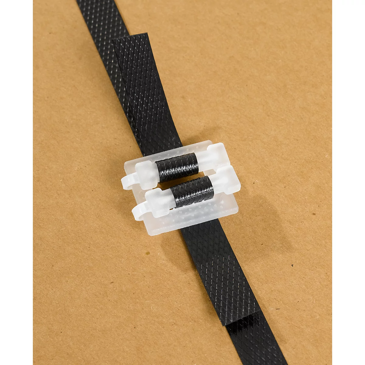 Black plastic strap with white clasp on brown background.