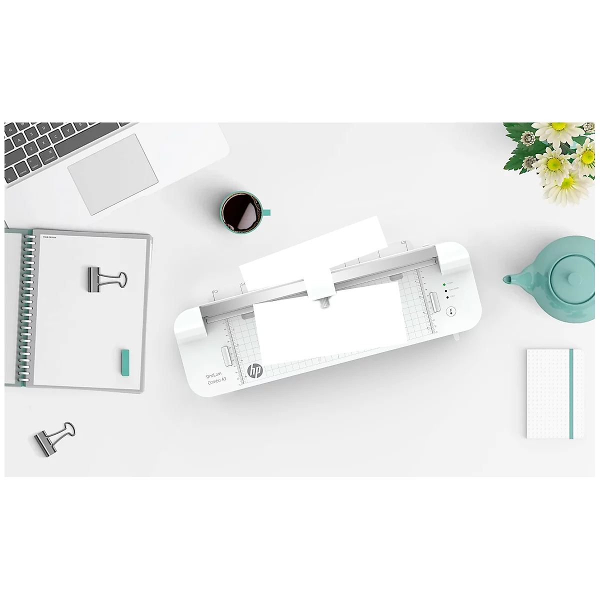 Vue de dessus d'un bureau avec une imprimante, un ordinateur portable, un carnet, une tasse, une théière et des fleurs. Tous les éléments sont blancs ou gris clair.