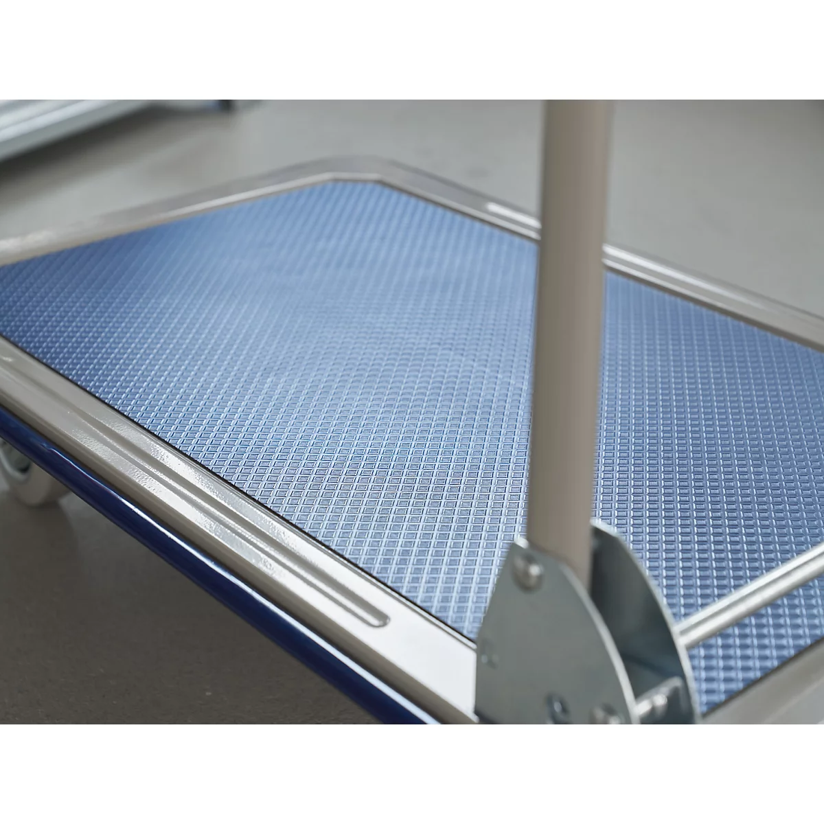 Close-up of a blue trolley floor with a grid pattern and frame, with handle.