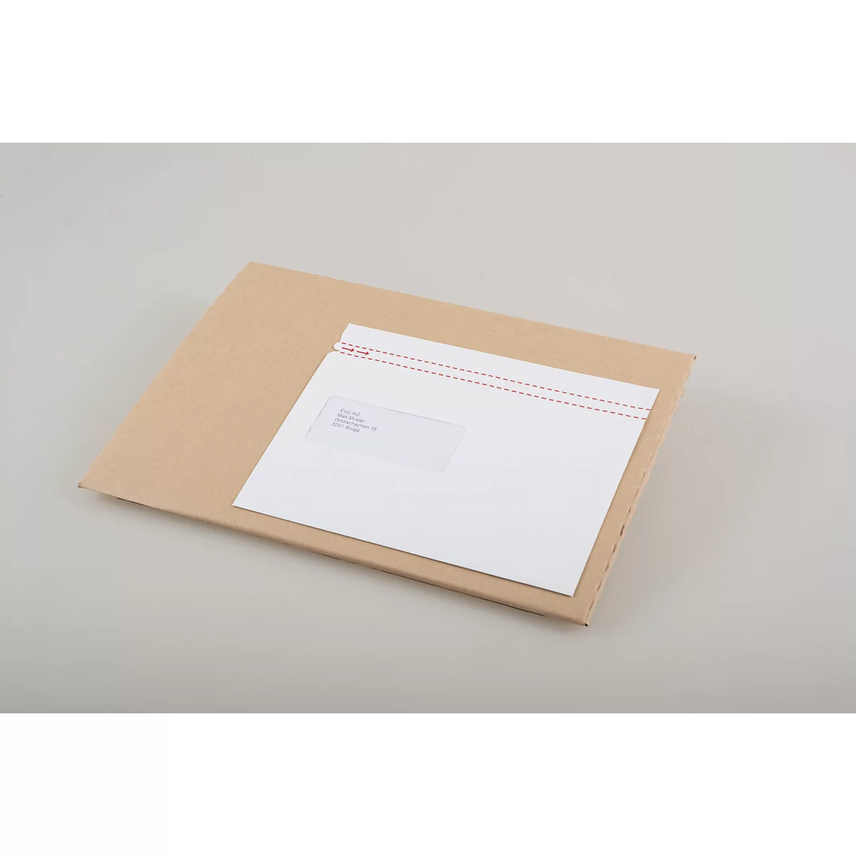 Une enveloppe et une carte postale sont posées sur une base en carton brun.