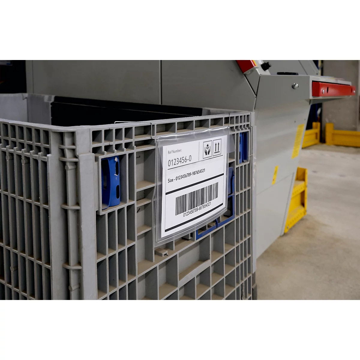 Conteneur en plastique gris avec étiquette. L'étiquette affiche des chiffres, des codes-barres et des symboles.