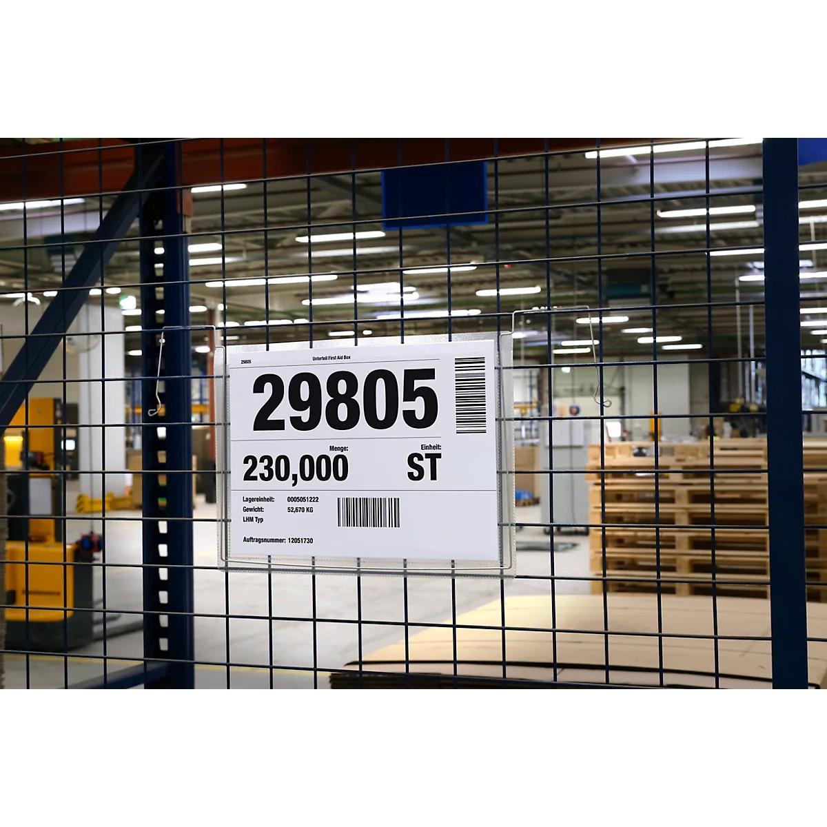 Panneau indiquant 29805, 230 000 ST, et codes-barres dans un entrepôt, derrière une grille.