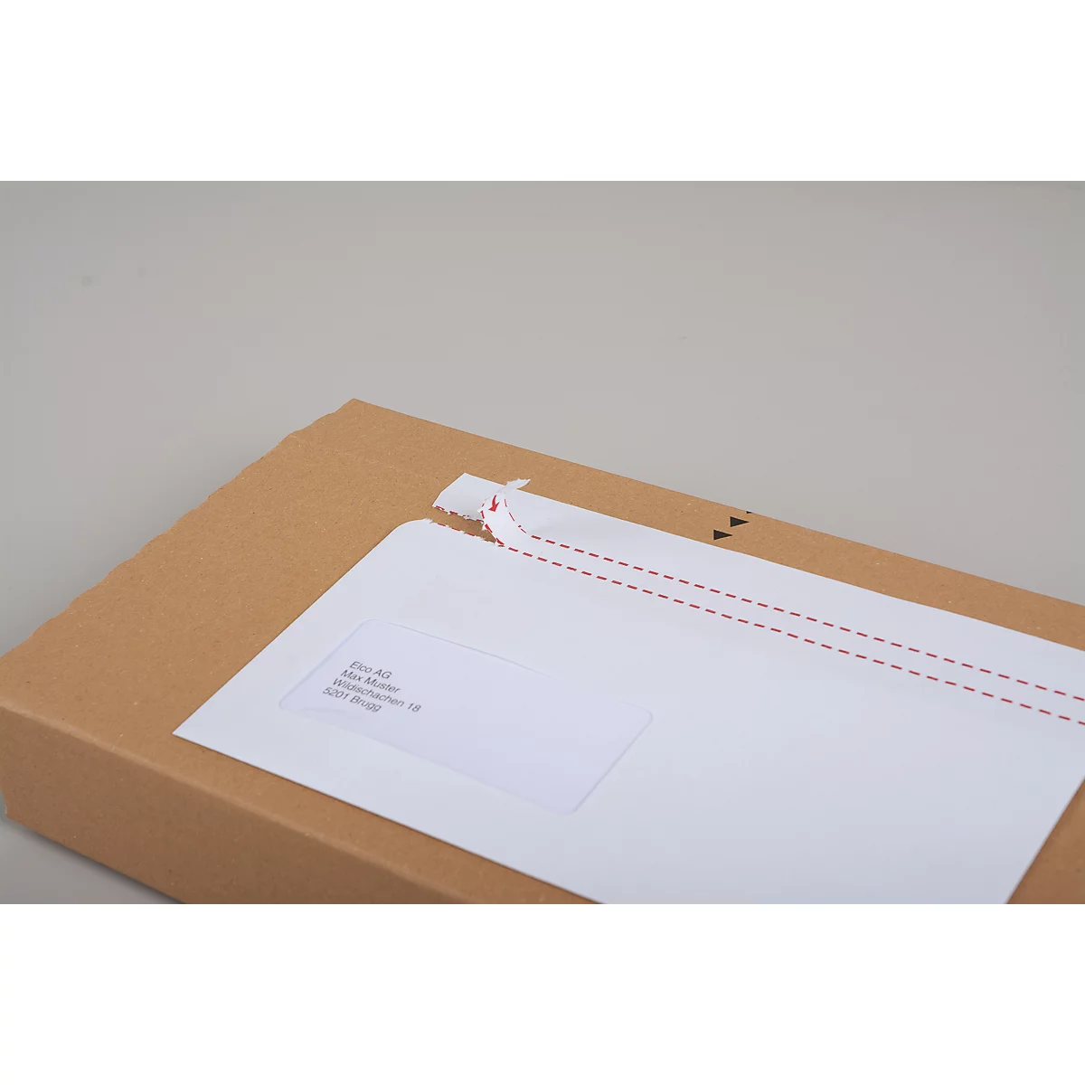 Une boîte en carton marron avec une enveloppe blanche. L'enveloppe a une perforation avec une couture rouge.