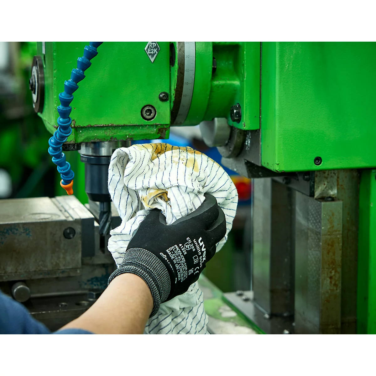 Een persoon veegt een werktuigmachine af met een doek. Ze dragen een zwarte handschoen.