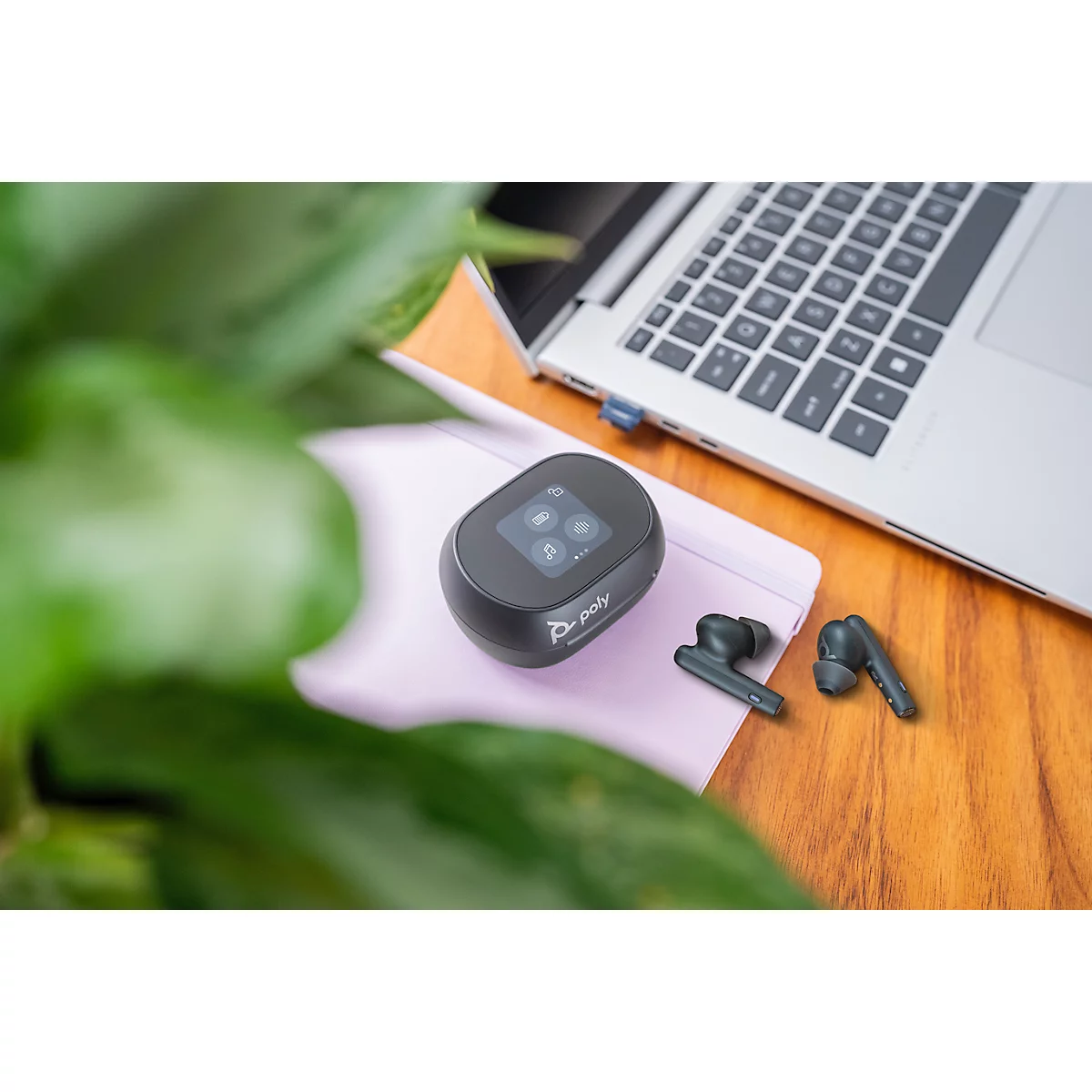 Black mobile Wi-Fi router, wireless earbuds, and laptop on a wooden desk. Symbols on screen.