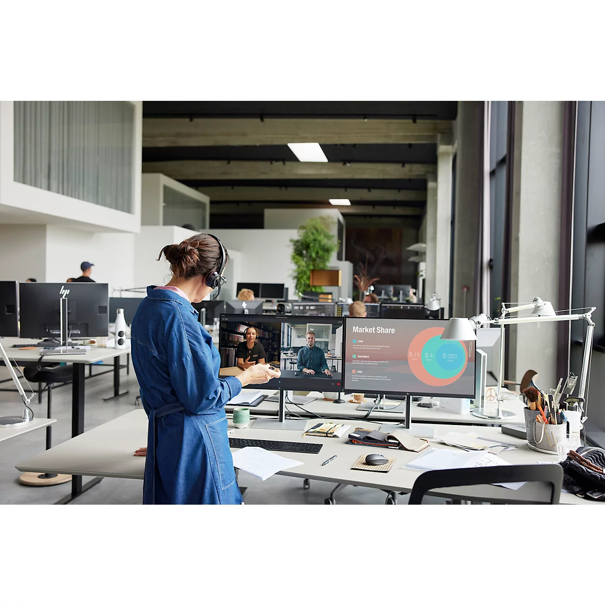 A woman in a denim dress during a video conference in the office. Charts on the screen.