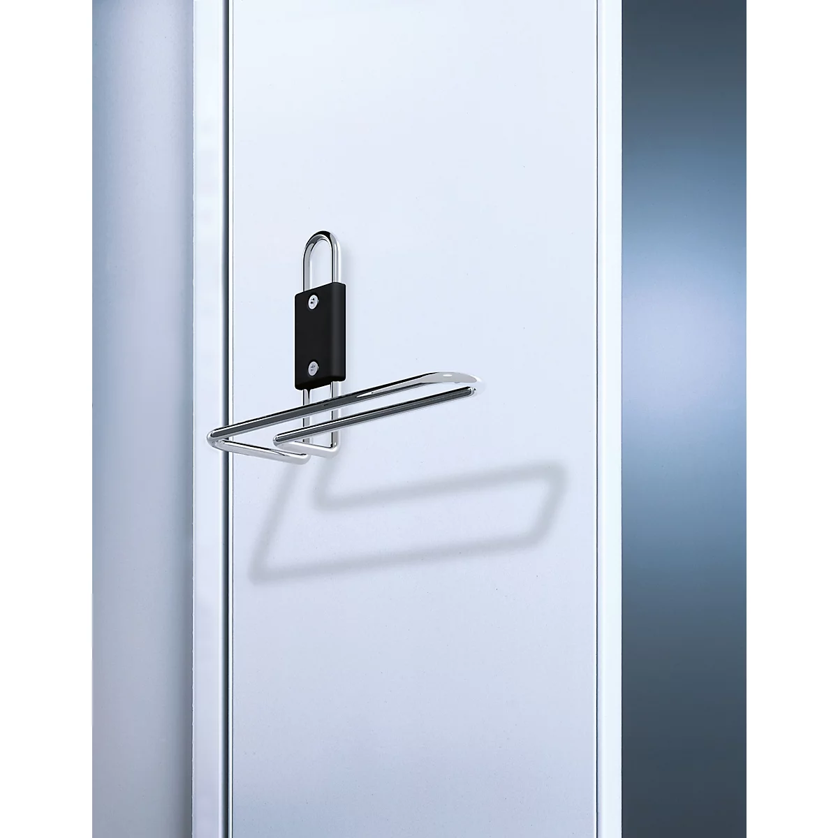 Porte-serviettes. Cadre métallique avec support noir, monté sur une porte blanche, ombre visible.