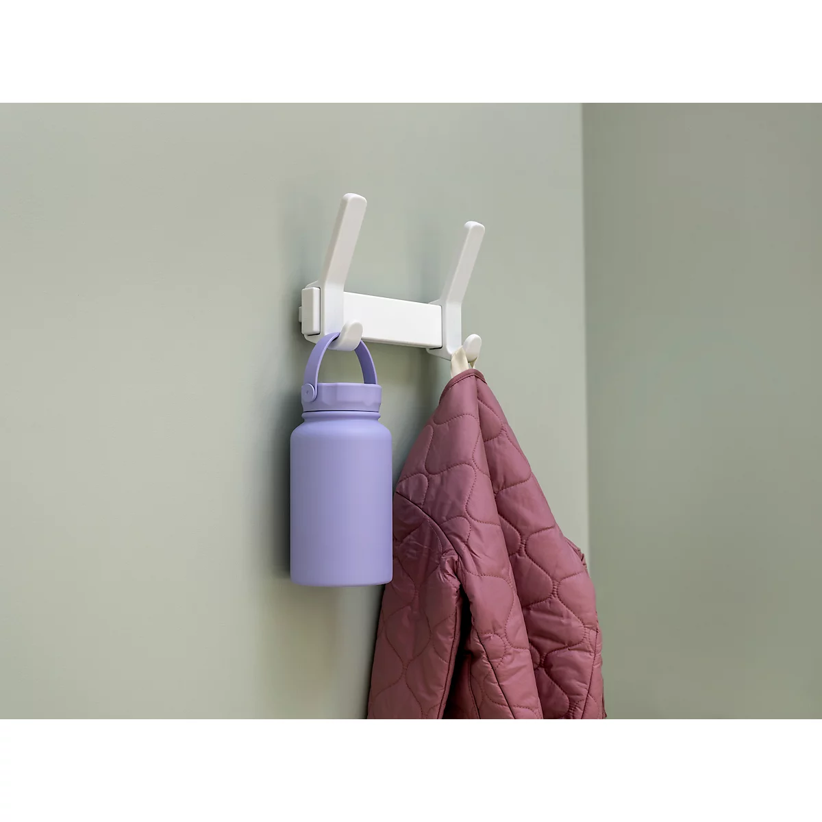 Crochet blanc fixé à un mur avec une gourde violette et une veste rose.