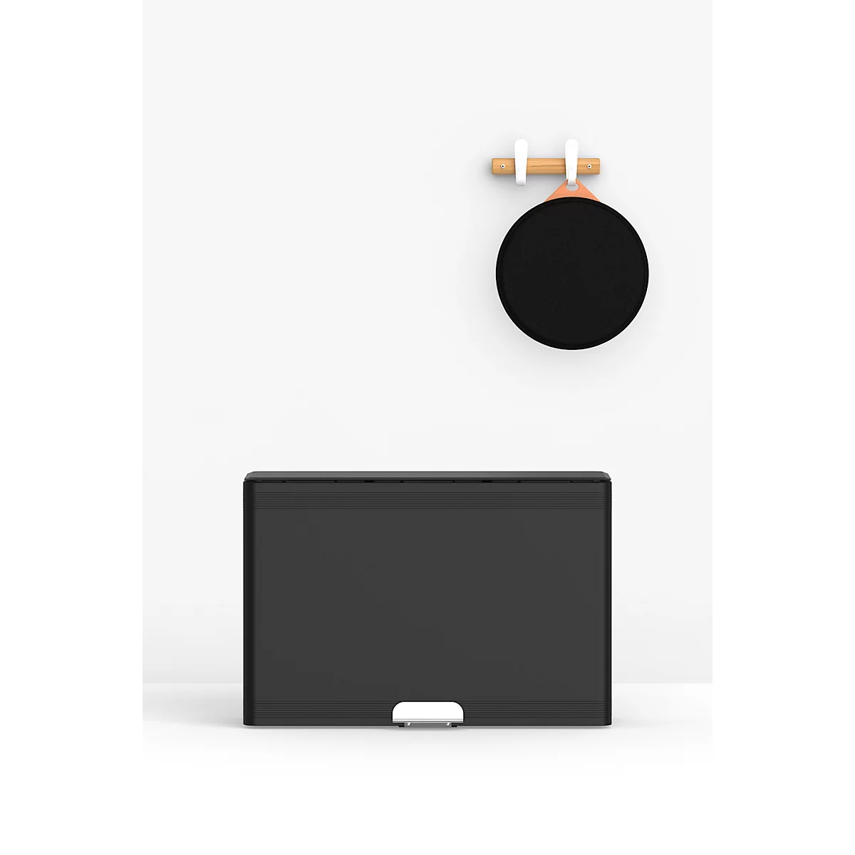 Une poubelle noire sur fond blanc. Au-dessus est accroché un panneau rond noir.