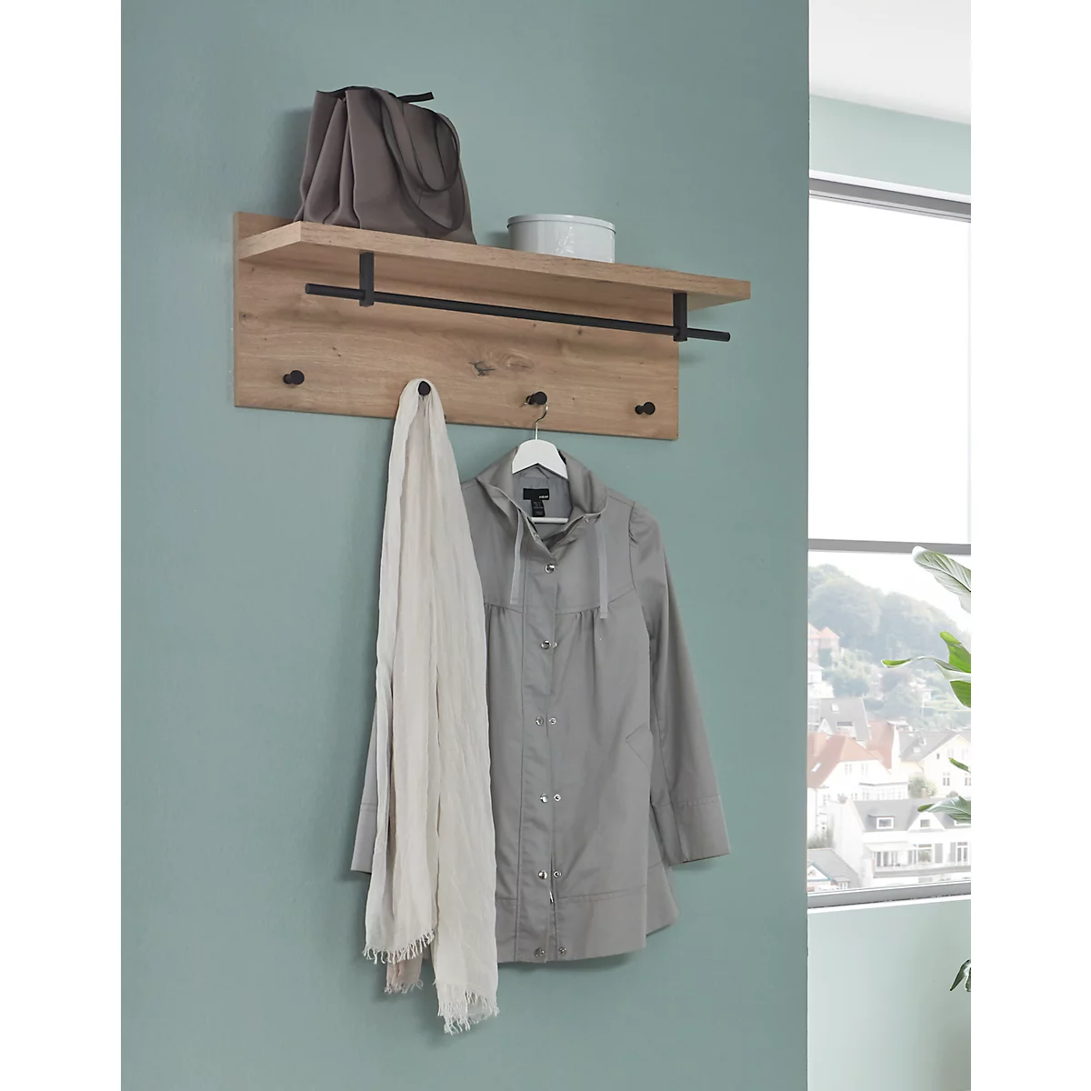 Porte-manteau mural en bois avec vêtements, écharpe et sac. Une fenêtre avec vue est accrochée au mur.