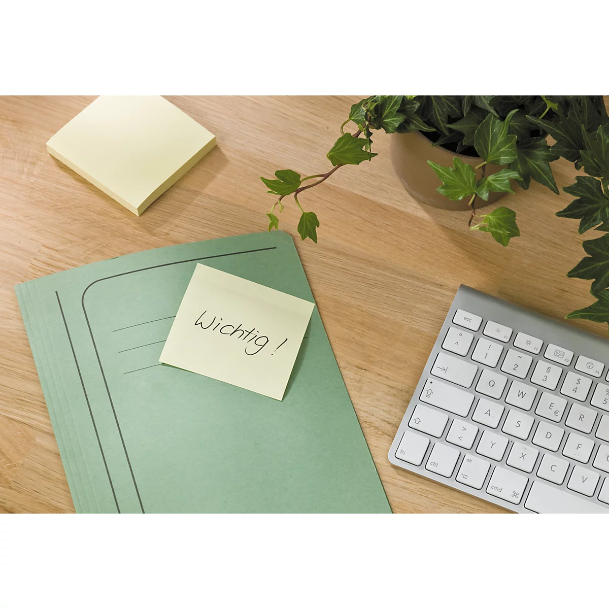 Bureau avec un post-it indiquant "Important!", un dossier, un clavier et une plante.