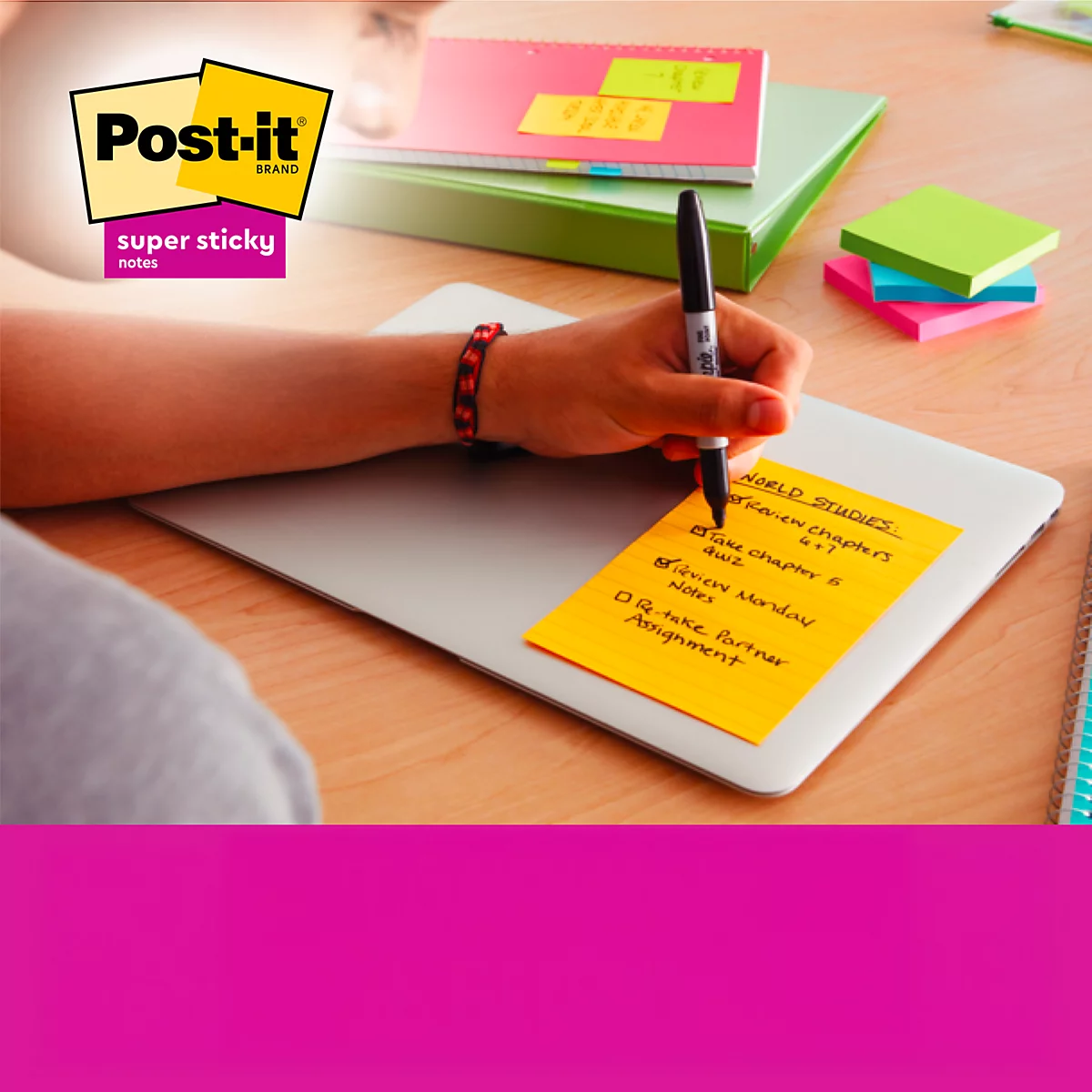 Persoon schrijft met een pen op een gele Post-it-briefje dat op een laptop geplakt zit. Meer post-it-briefjes in de buurt.