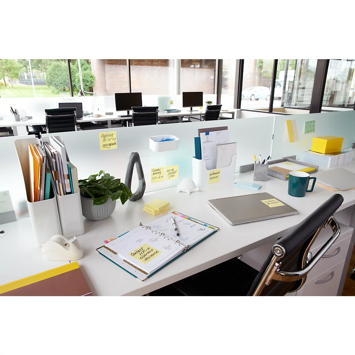 Espace de travail de bureau avec des post-it, des stylos, des cahiers et un ordinateur portable.