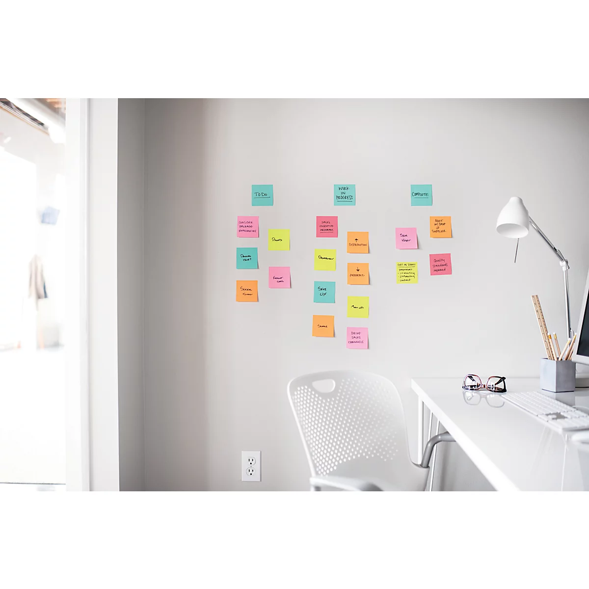Des post-it colorés sur un mur. Bureau, chaise, lampe, lunettes, crayons.