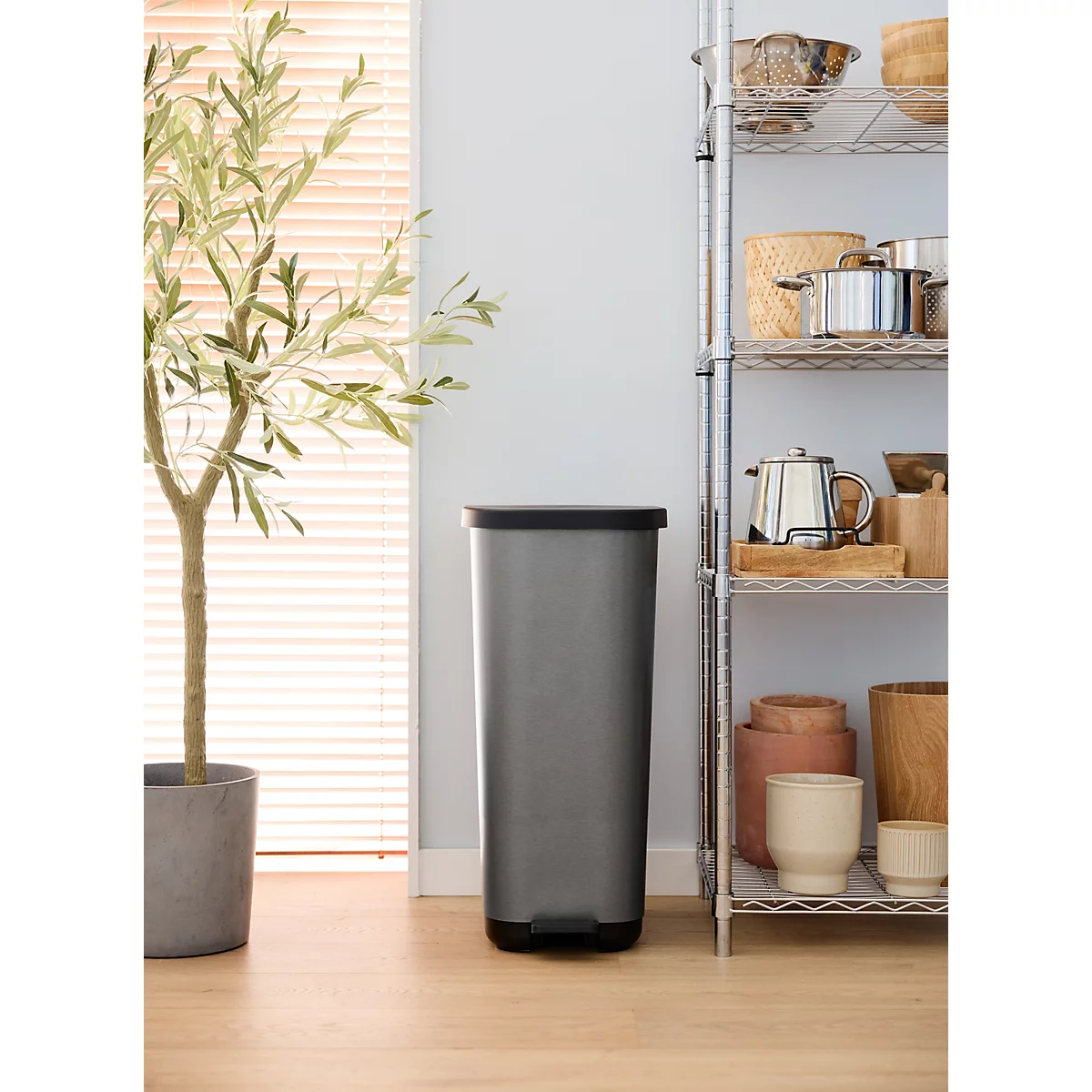 Poubelle grise avec couvercle et pédale, sur fond blanc.