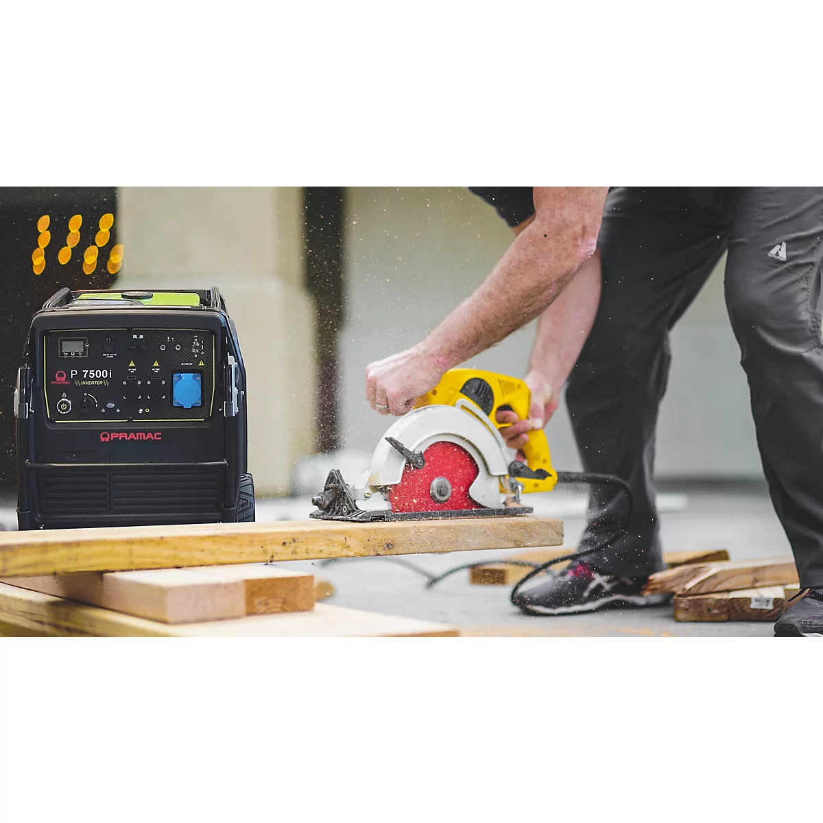 Ein mobiler Stromerzeuger steht neben einem Handwerker, der mit einer Kreissäge Holz zuschneidet.