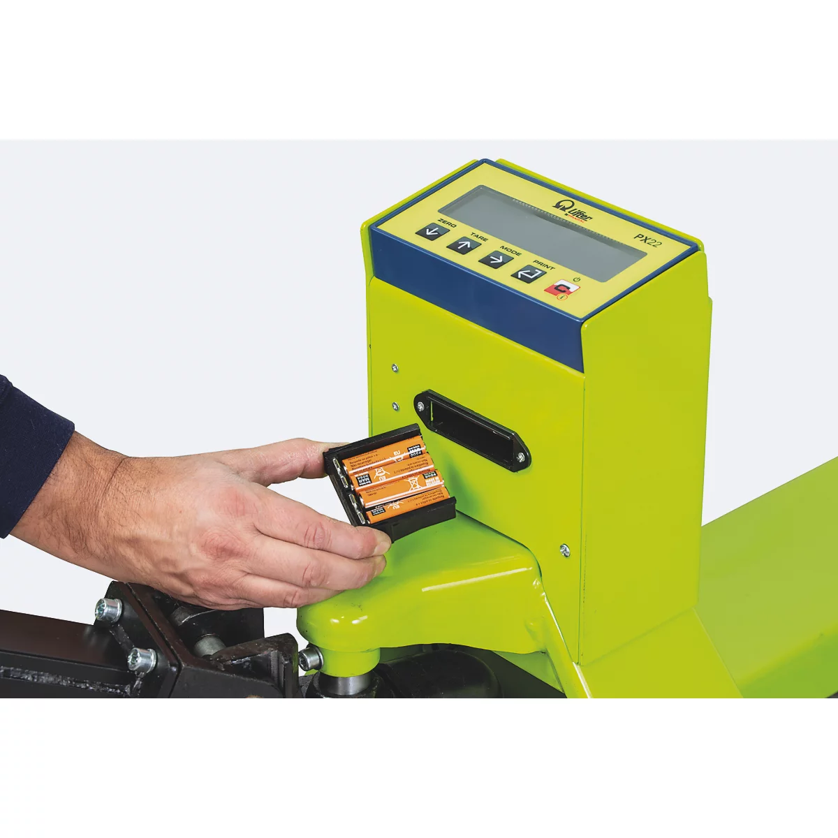 Close-up of a person inserting batteries into a yellow-green scale. "PK22" is visible on the display.