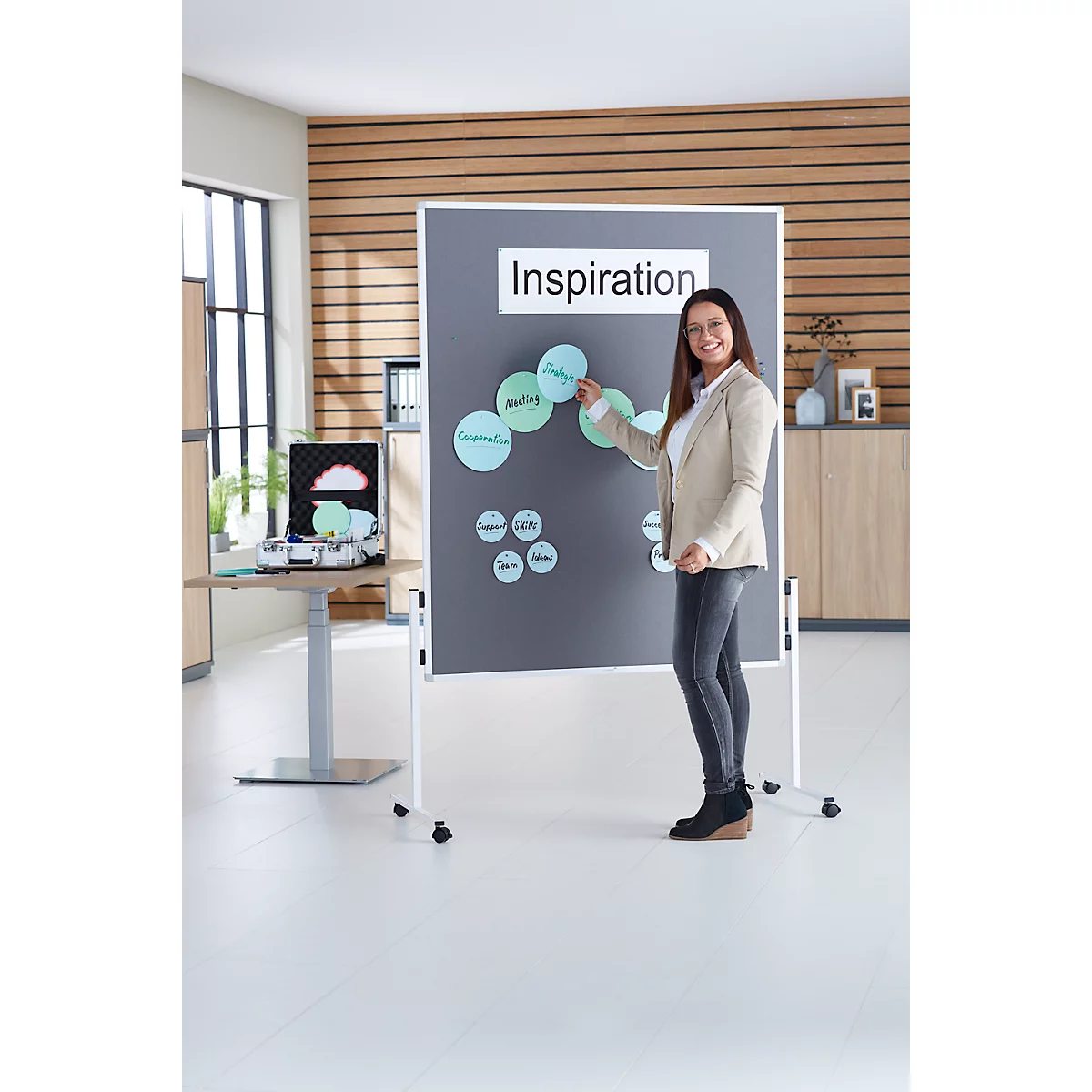 A woman presents in front of a flipchart. The flipchart says "Inspiration". Around it are circles with keywords.