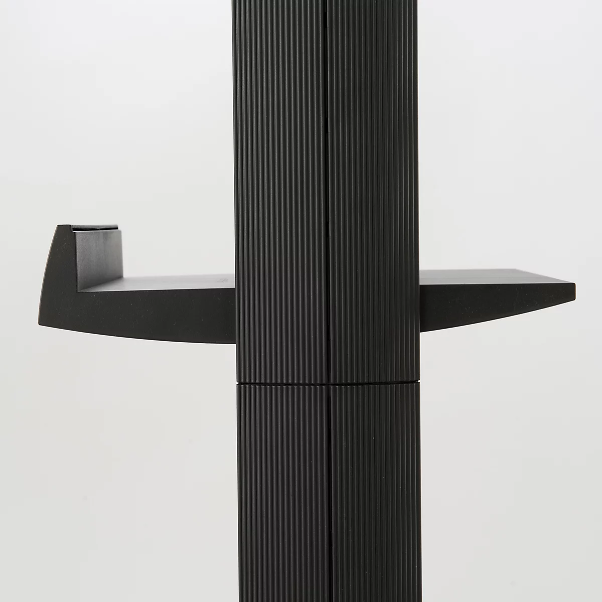Meuble noir avec une surface nervurée. Deux étagères à angle droit, une à gauche, une à droite.