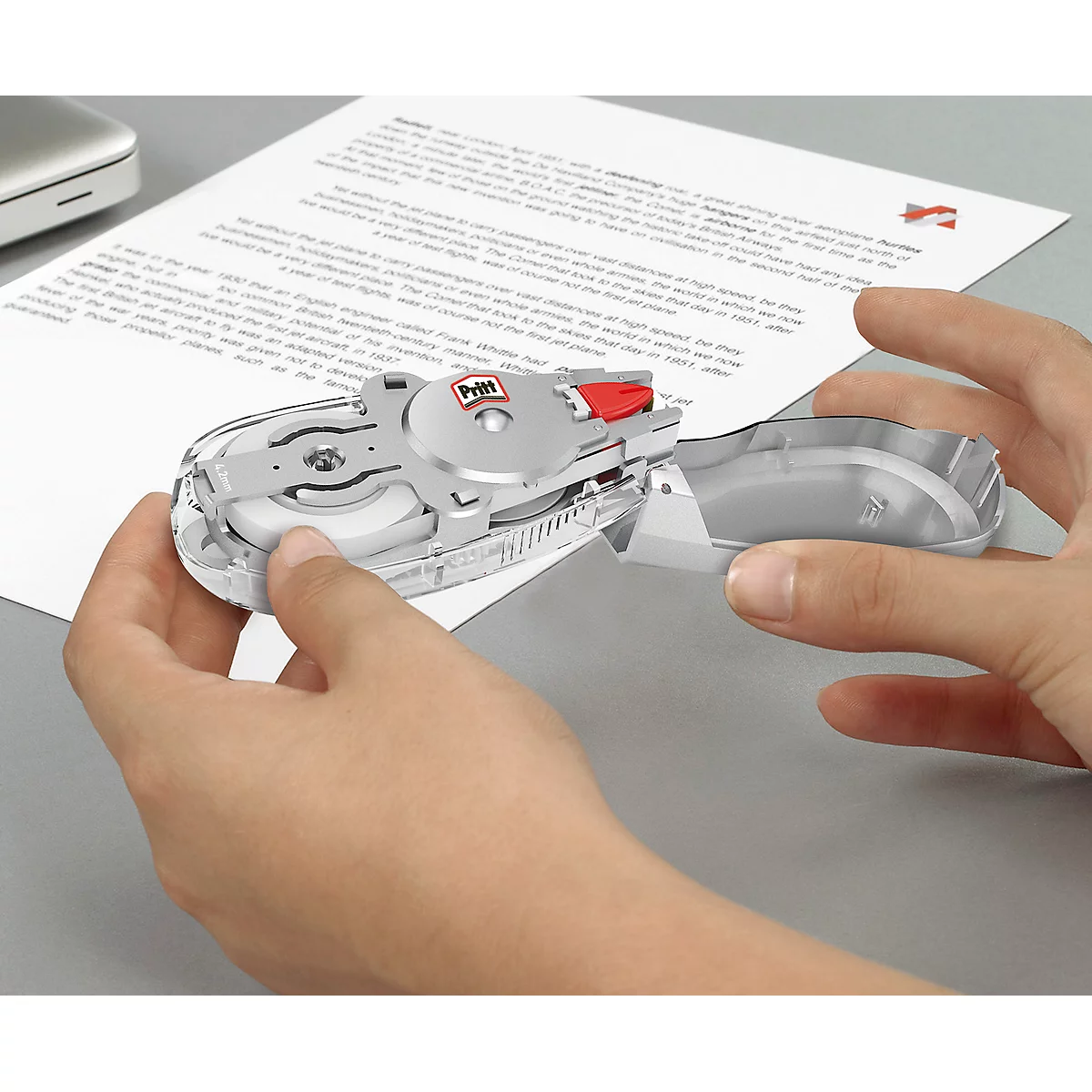 Hands holding a silver correction roller over a white sheet. The roller says "Pettit".