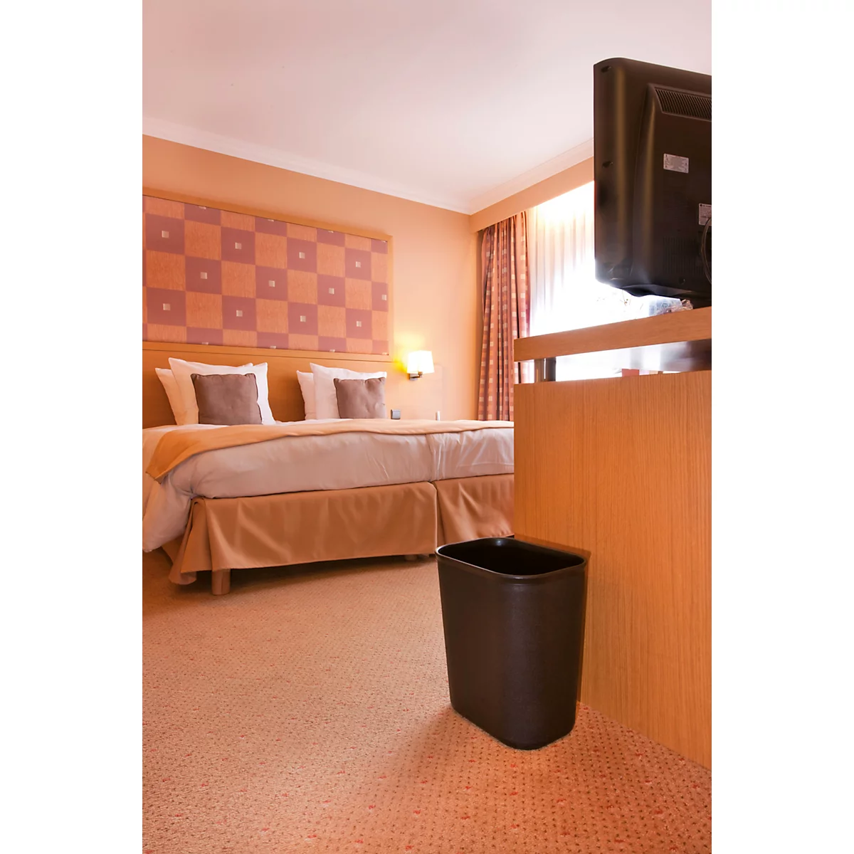 Hotelkamer met tweepersoonsbed, tv en vuilnisbak. De kamer is in warme tinten.