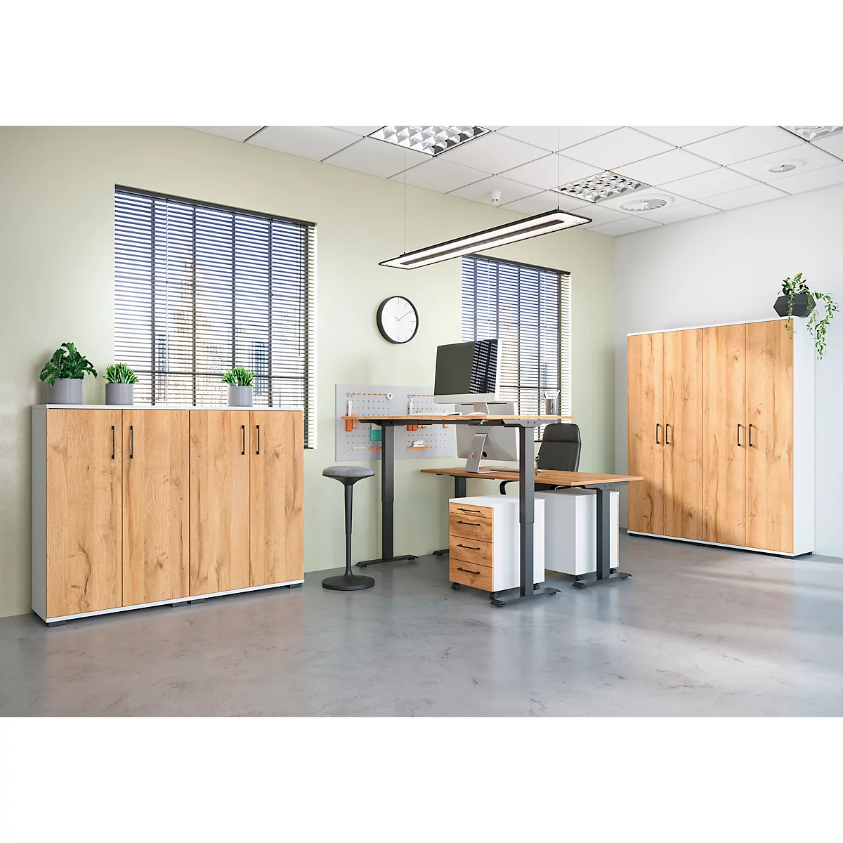 Een kantoorruimte met houten kasten en bureau. Een kast rechts, een kast links en een zit-sta combinatie.