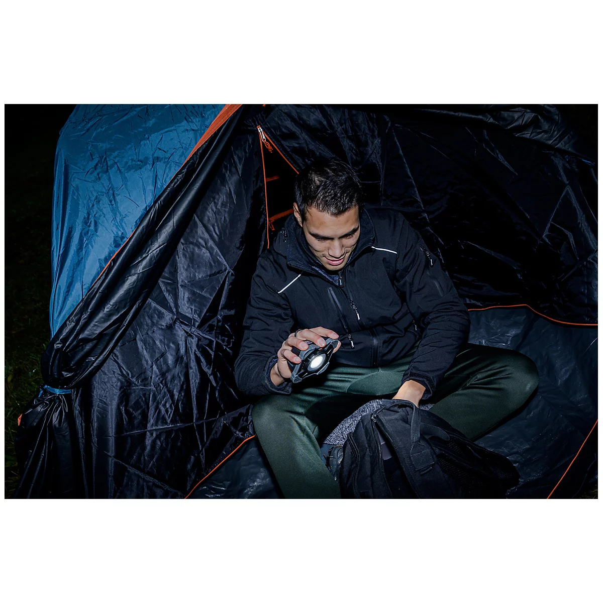 Un projecteur de travail carré avec des bords en caoutchouc gris, une LED lumineuse au centre et un interrupteur d'alimentation avec un indicateur d'énergie.