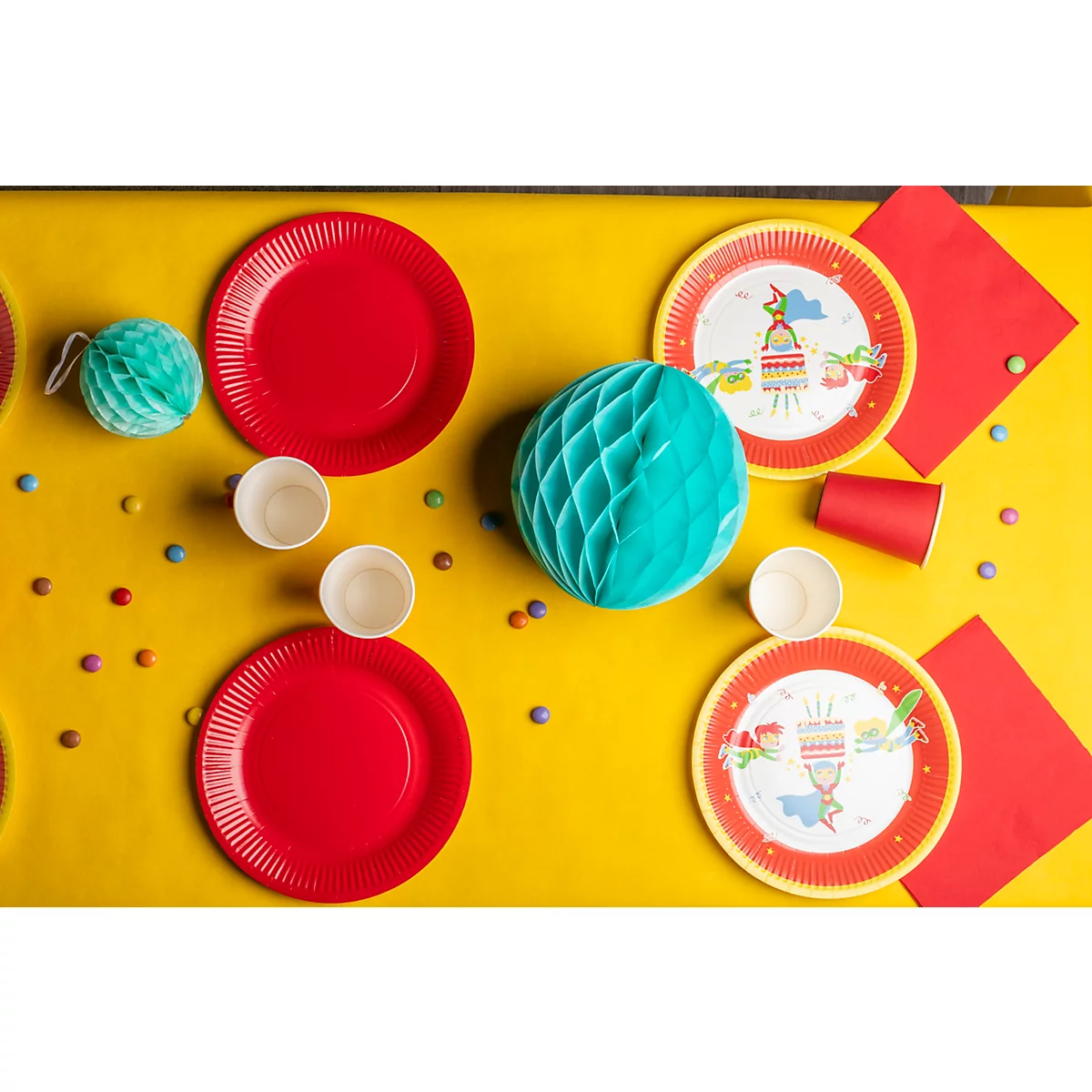 Vue aérienne d'une table de fête avec des fournitures de fête : assiettes, gobelets, serviettes et décorations.