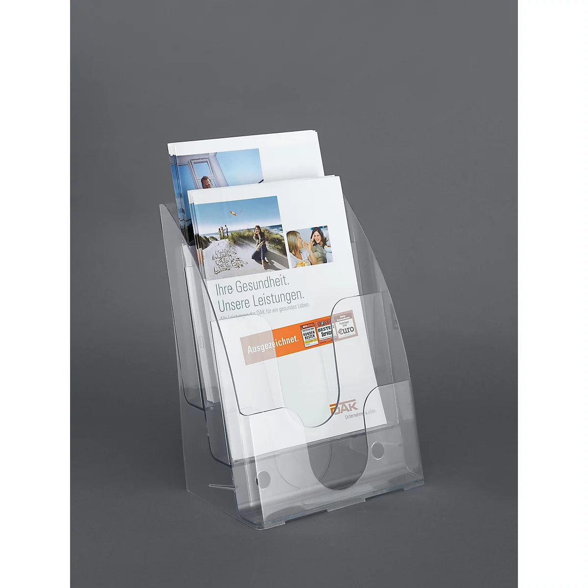 Transparenter Prospekthalter aus Acryl auf grauem Hintergrund mit Infobroschüren.