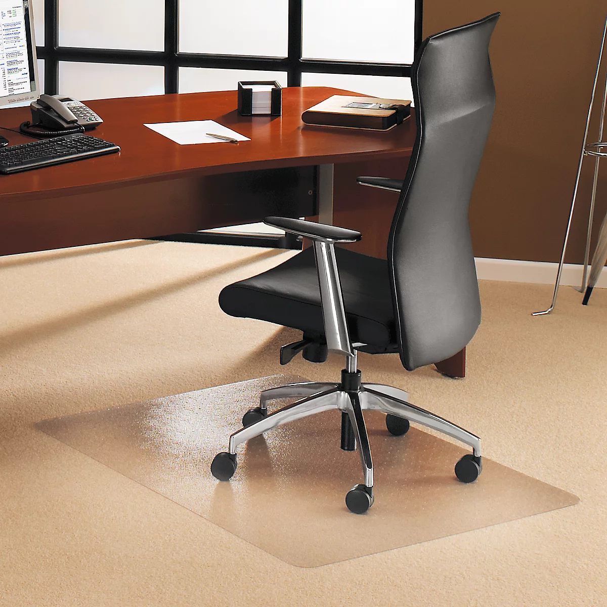 Office chair with mat in front of desk. The carpet is beige, the mat is transparent.