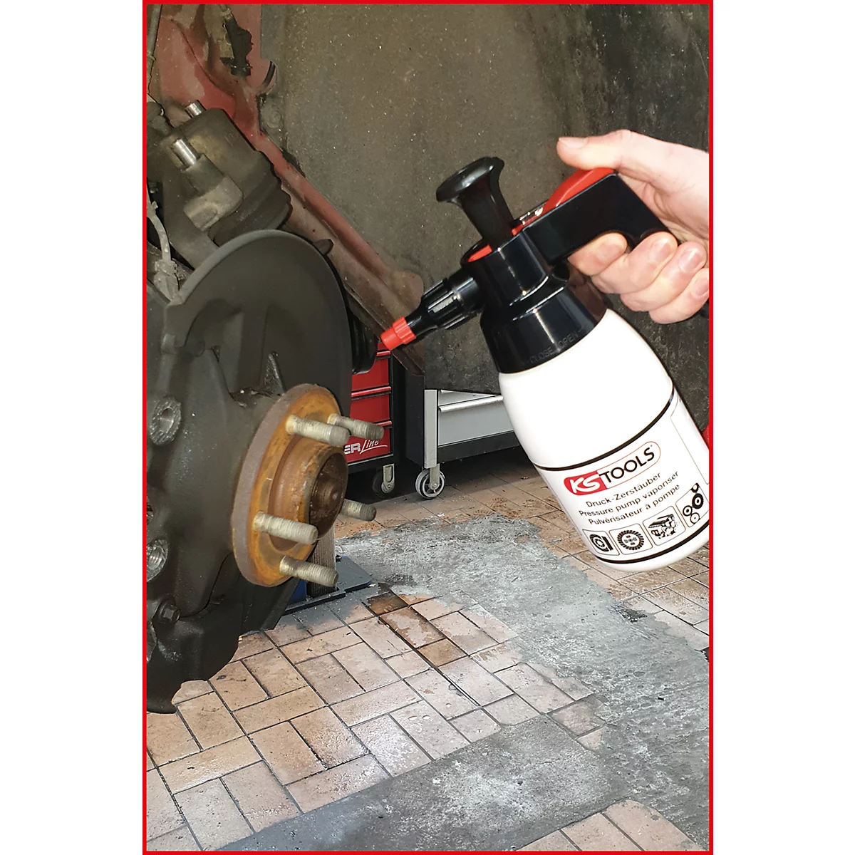 Person besprüht Bremsscheibe mit Reiniger von KS TOOLS. Aufschrift KS TOOLS auf der weißen Flasche.