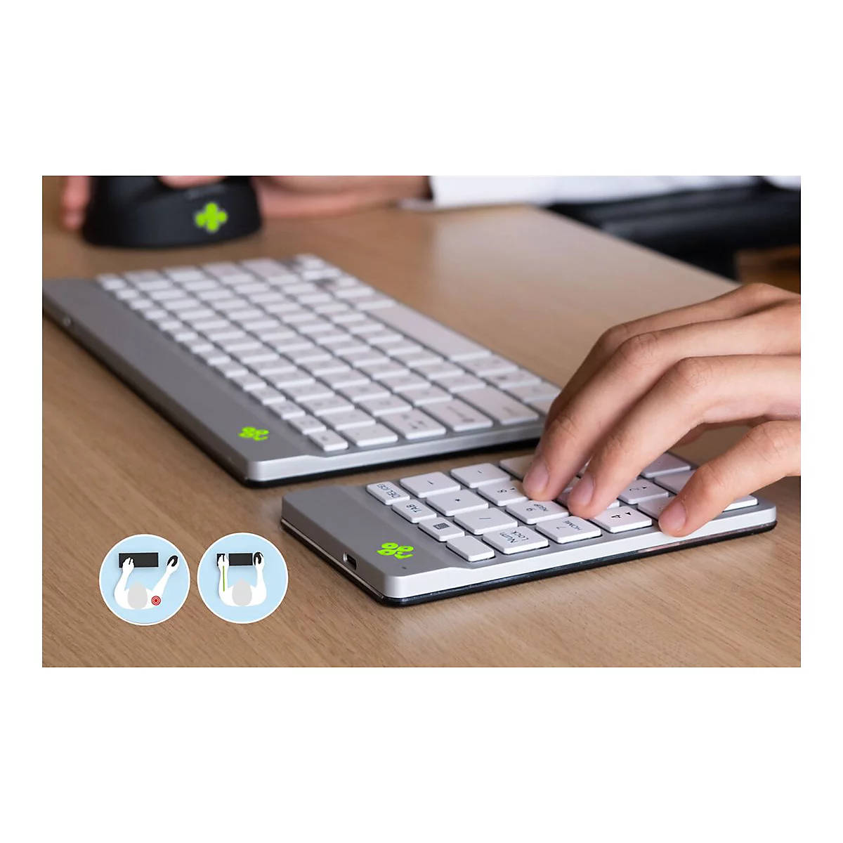 Hände nutzen eine ergonomische, getrennte Tastatur und ein separates Ziffernfeld auf einem Holztisch.