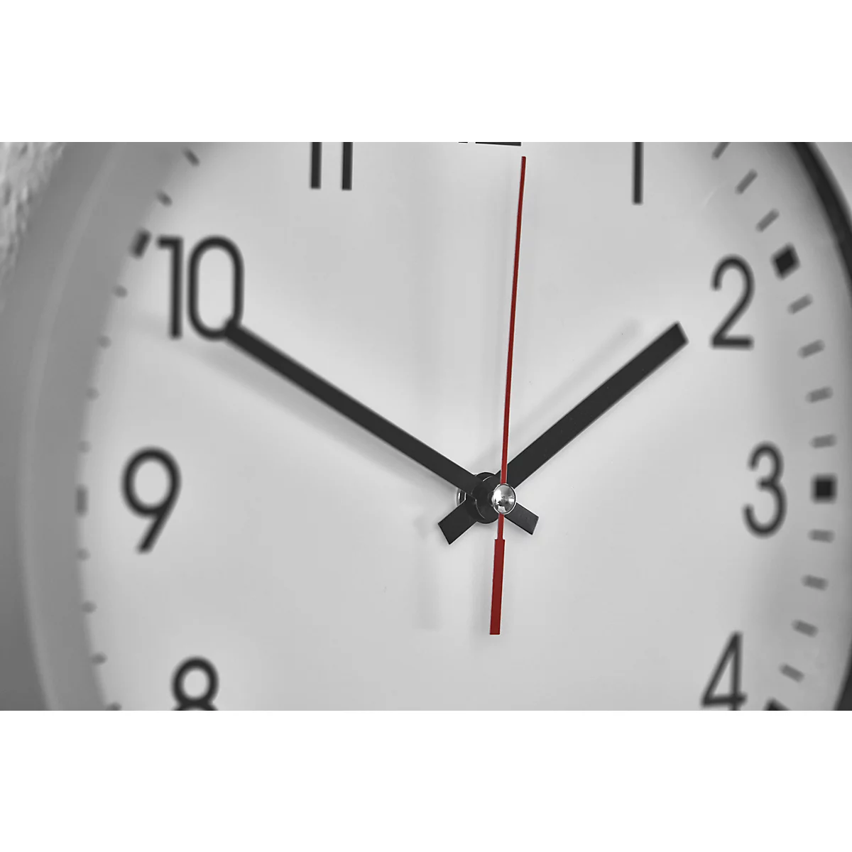 Close-up of a clock. Black hands point to 2:10. Red second hand. White clock face with black numbers.
