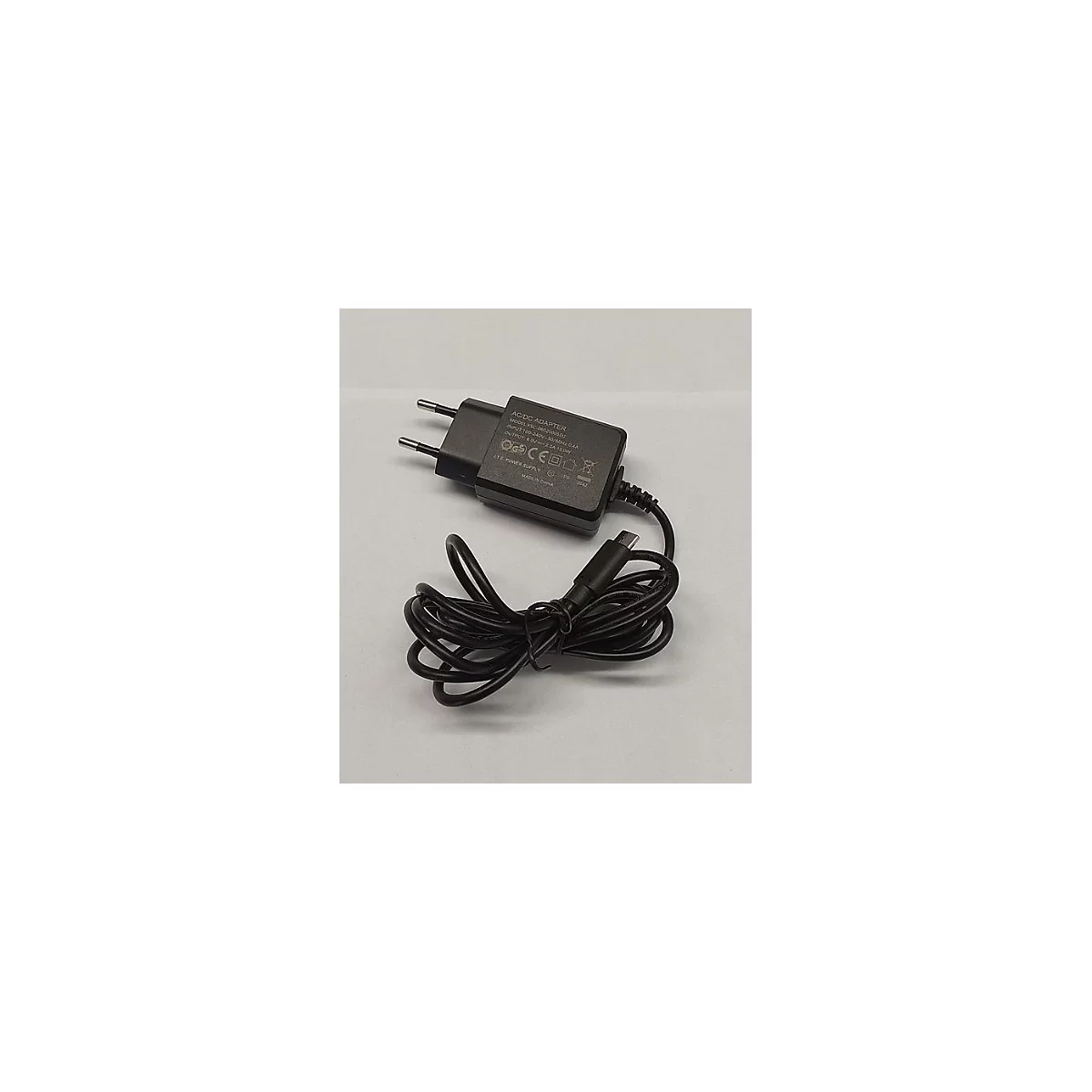 Schwarzes Netzteil mit Eurostecker und fest verbundenem Kabel mit USB-C-Anschluss auf hellem Hintergrund.