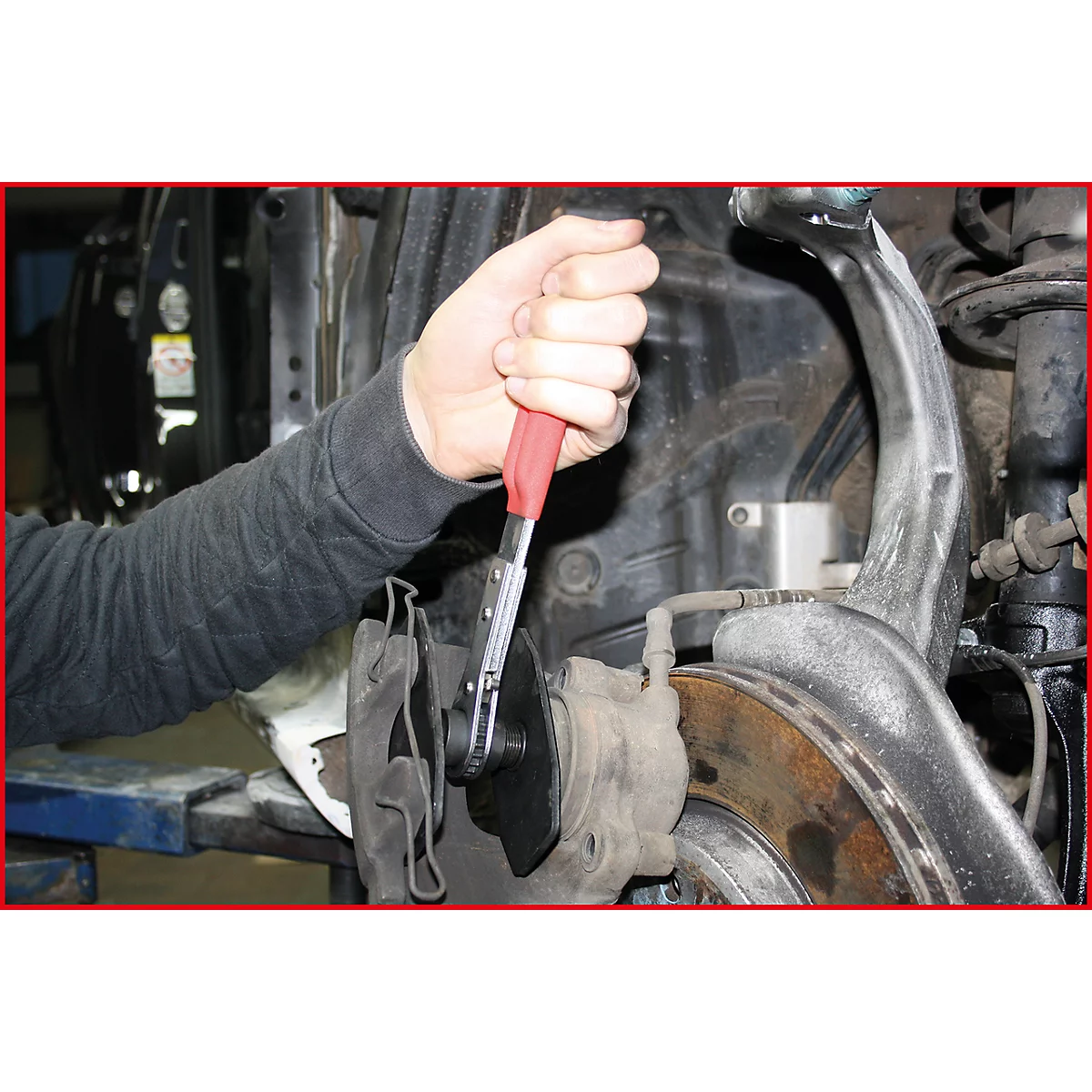 Eine Hand bedient eine Spezialzange an einer Bremsscheibe. Der Fokus liegt auf dem Werkzeug und dem Bremssystem.