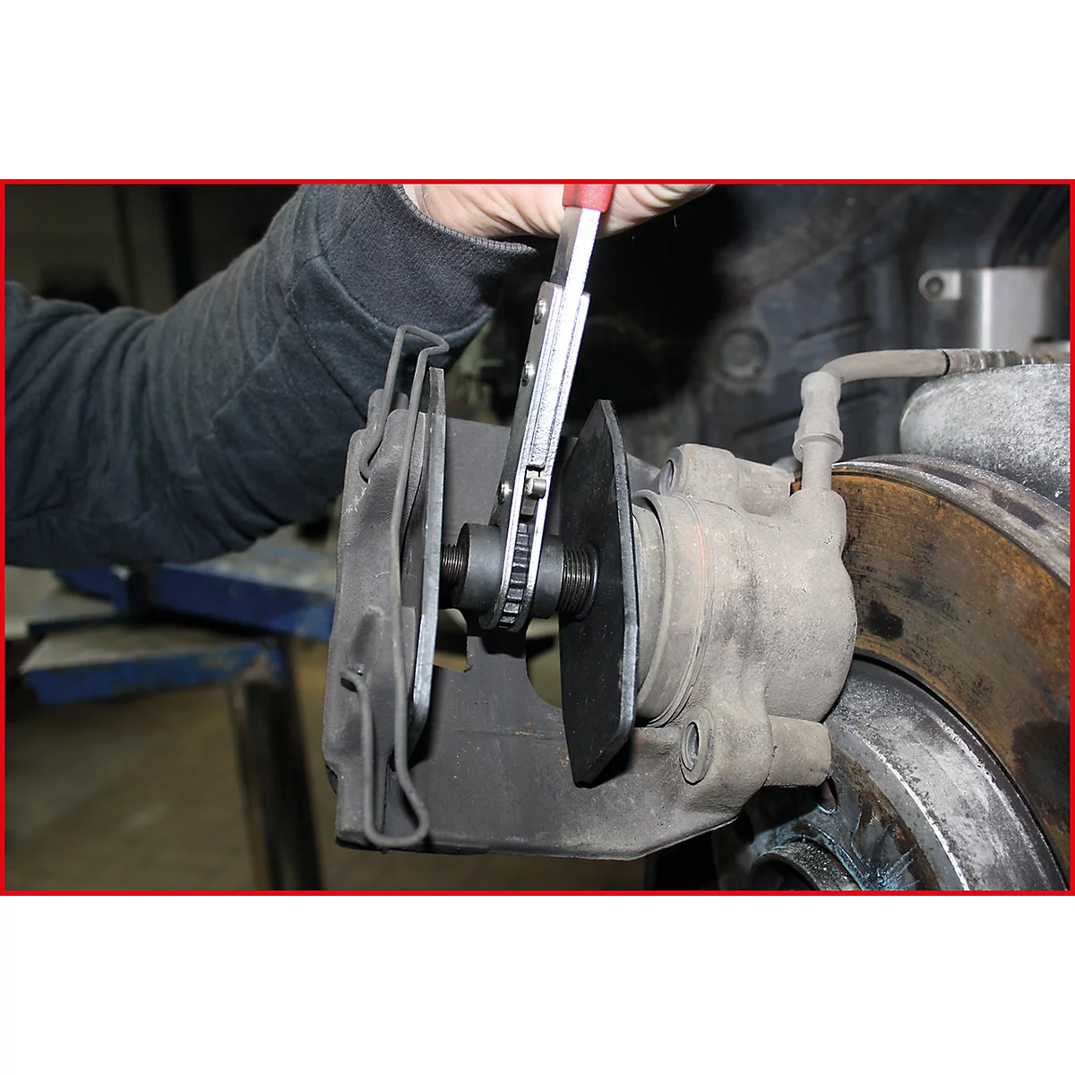 Eine Person benutzt eine Zange, um eine Bremsscheibe an einem Autoreifen zu bearbeiten.