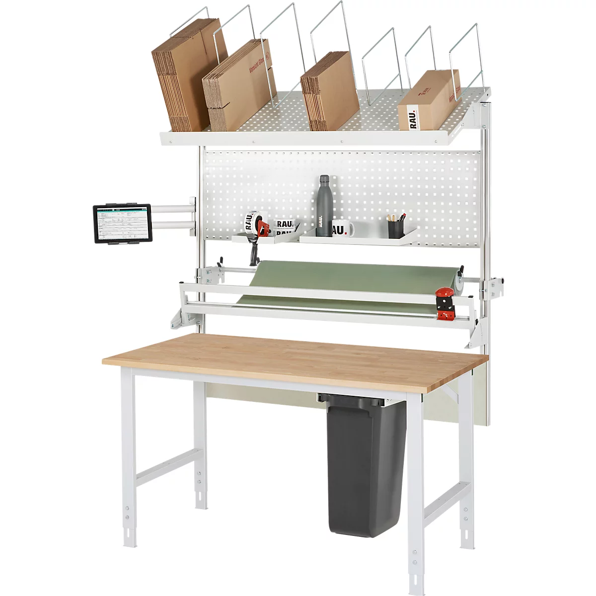 Arbeitstisch mit Packstation. Auf der oberen Ablage Kartons, in der Mitte Packpapier und ein Tablet. Unter dem Tisch eine Mülltonne.
