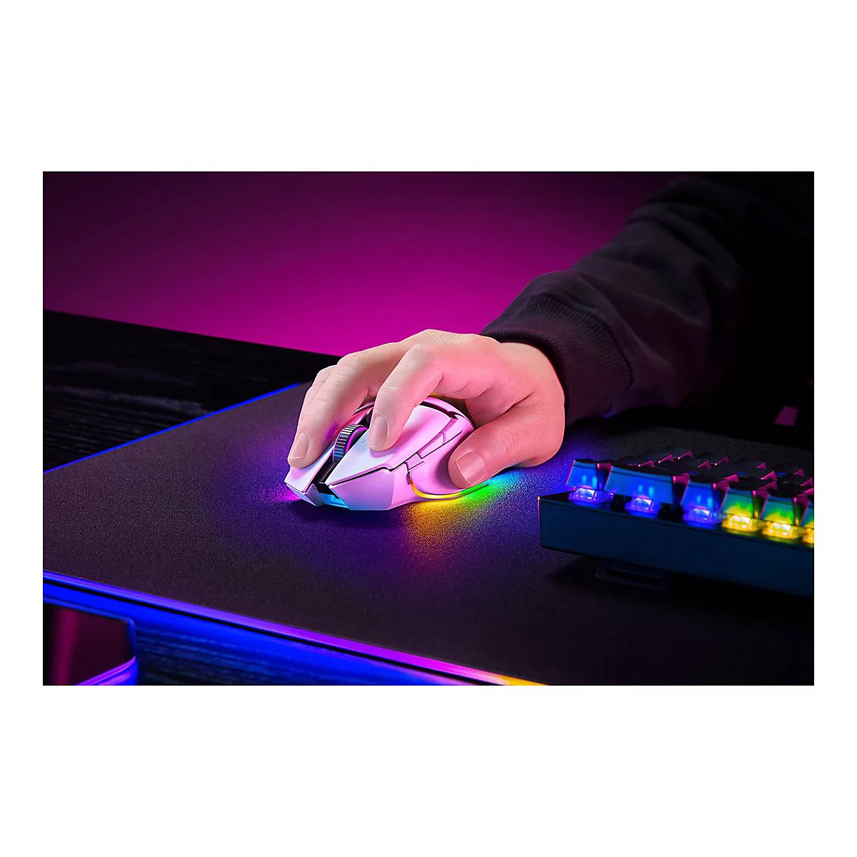 Eine Hand bedient eine weiße Gaming-Maus auf einem Mauspad. Ein Teil einer beleuchteten Tastatur ist zu sehen.