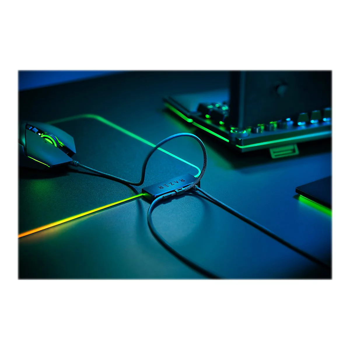 Gaming-Maus mit Kabel, Razer-Logo, RGB-Beleuchtung auf Mauspad und Tastatur. Dunkler Hintergrund mit Neonlicht.