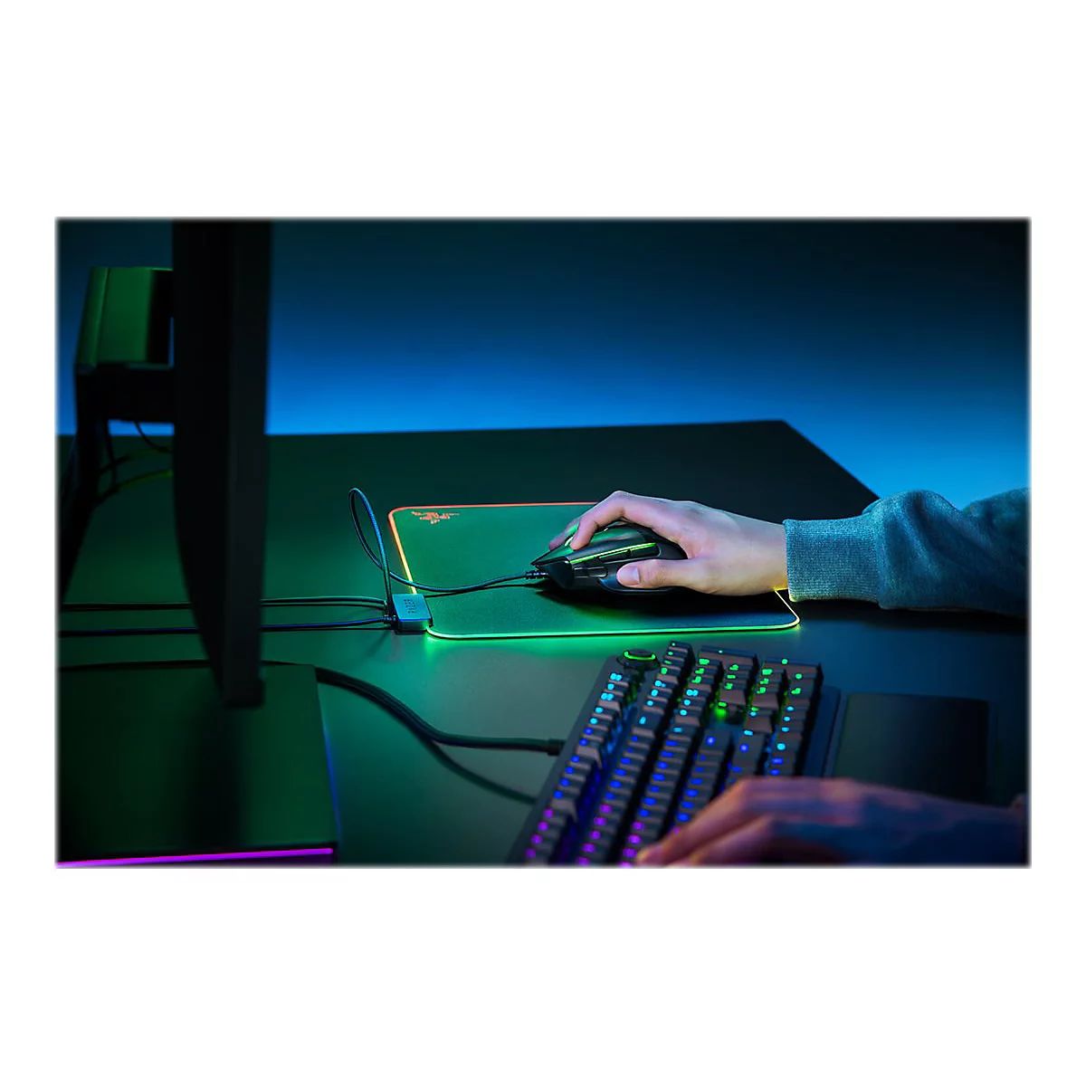 Hand auf einer Gaming-Maus, beleuchtetes Mauspad, beleuchtete Tastatur. Die Szene ist in Blau- und GrÃ¼ntÃ¶nen gehalten.