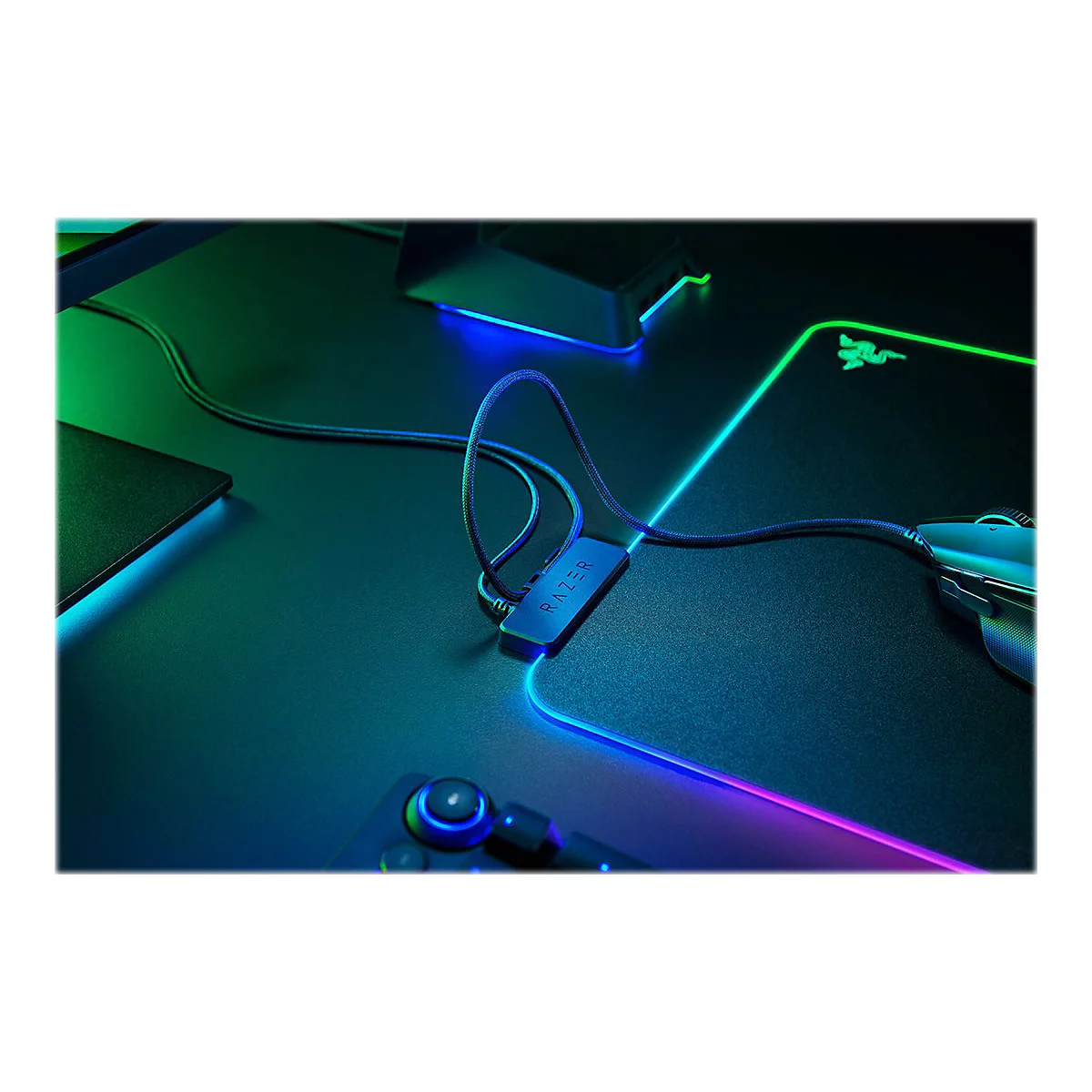 Schreibtisch mit Razer-Maus, Mauspad und Kabelhalter. Das Mauspad leuchtet in Neonfarben.