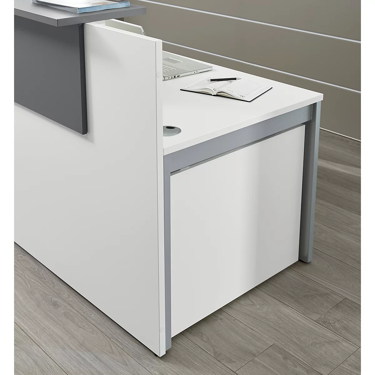 White reception desk with gray accents. On the surface are a notepad and a pen.