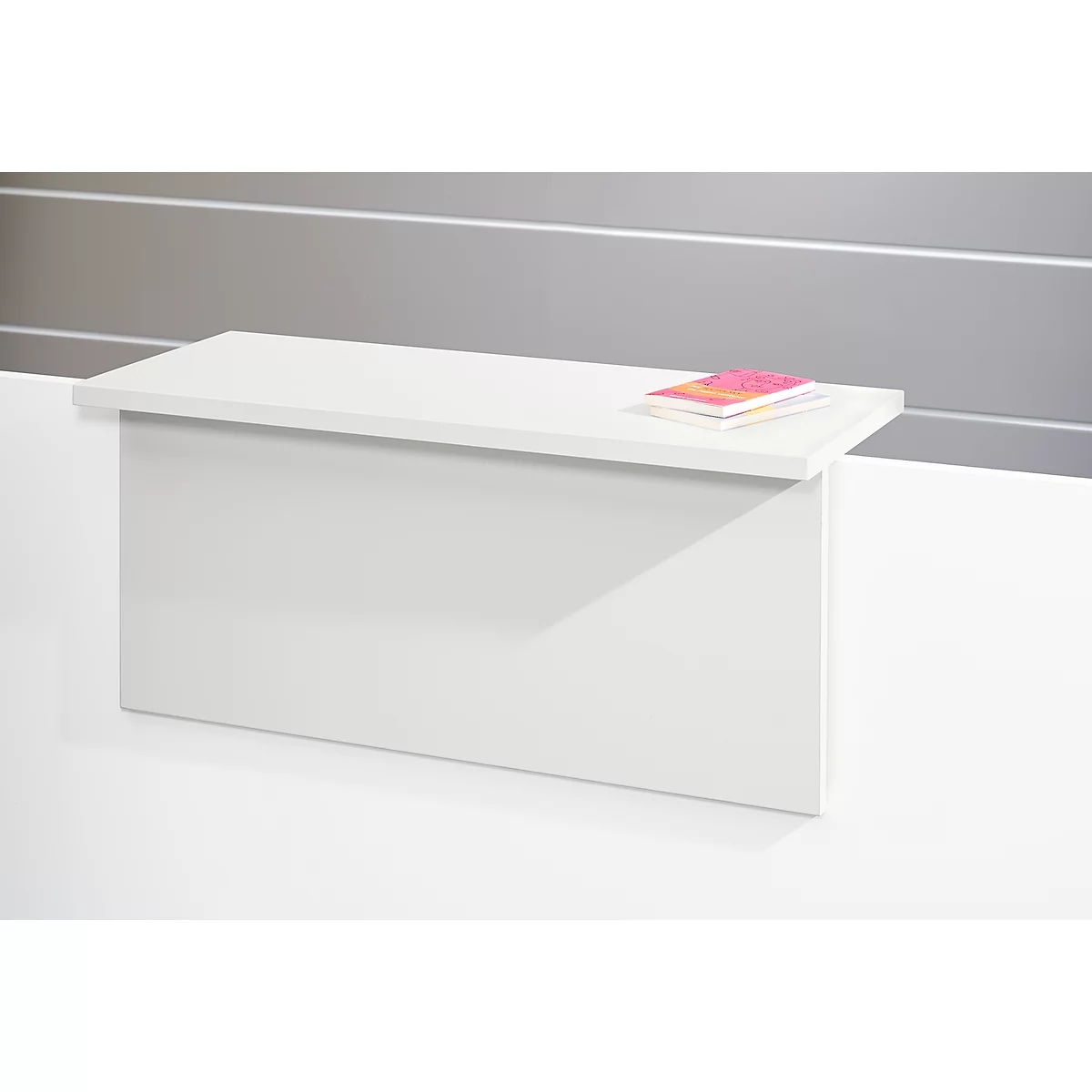 White table with two books. The table stands in front of a gray wall.