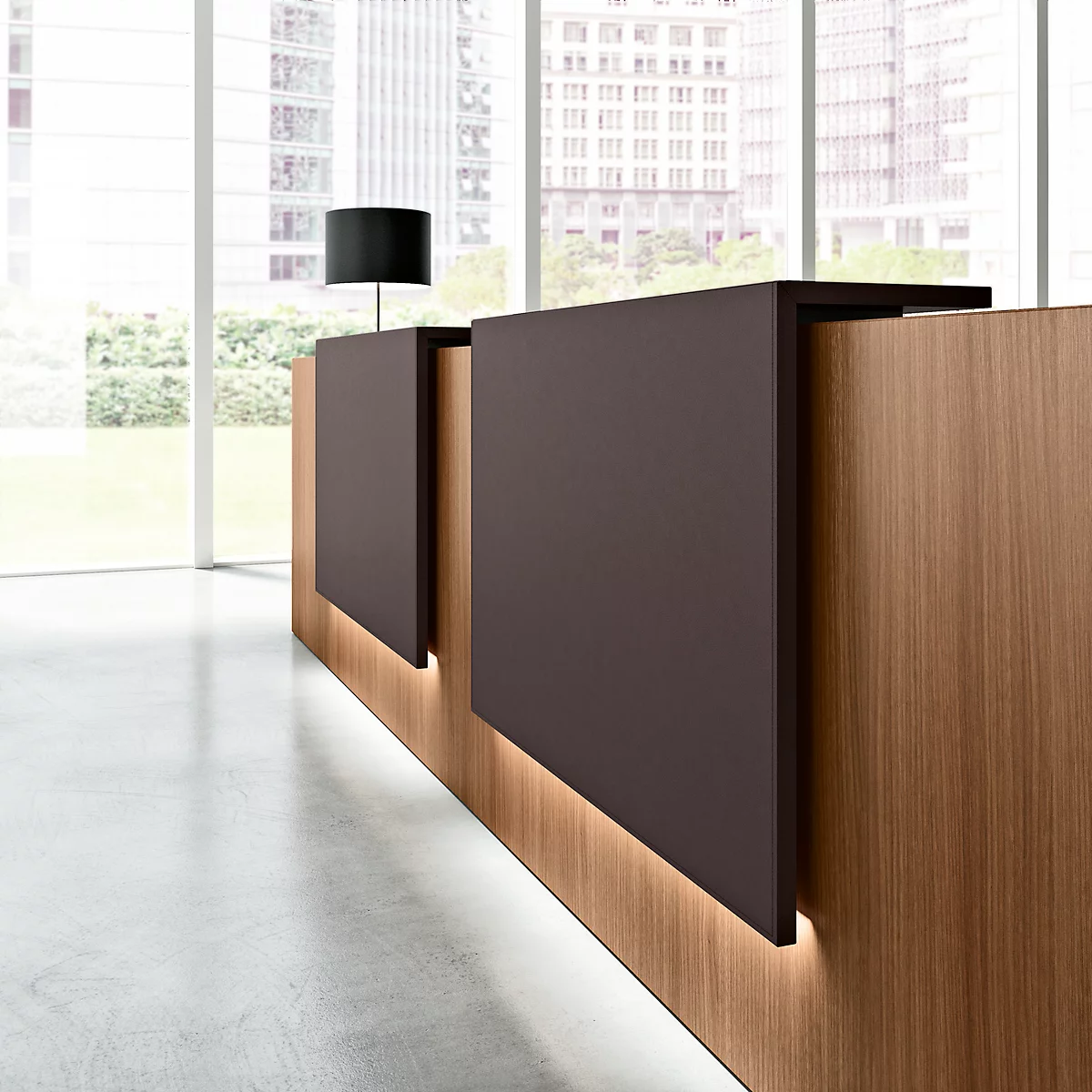 Reception desk with wood paneling and brown elements, windows in the background with a view of high-rise buildings.