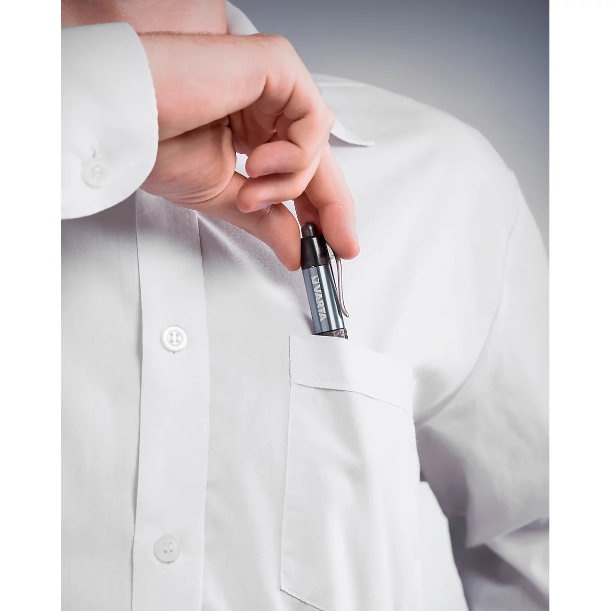 A person putting a pen into the breast pocket of a white shirt. The pen has a metal clip.
