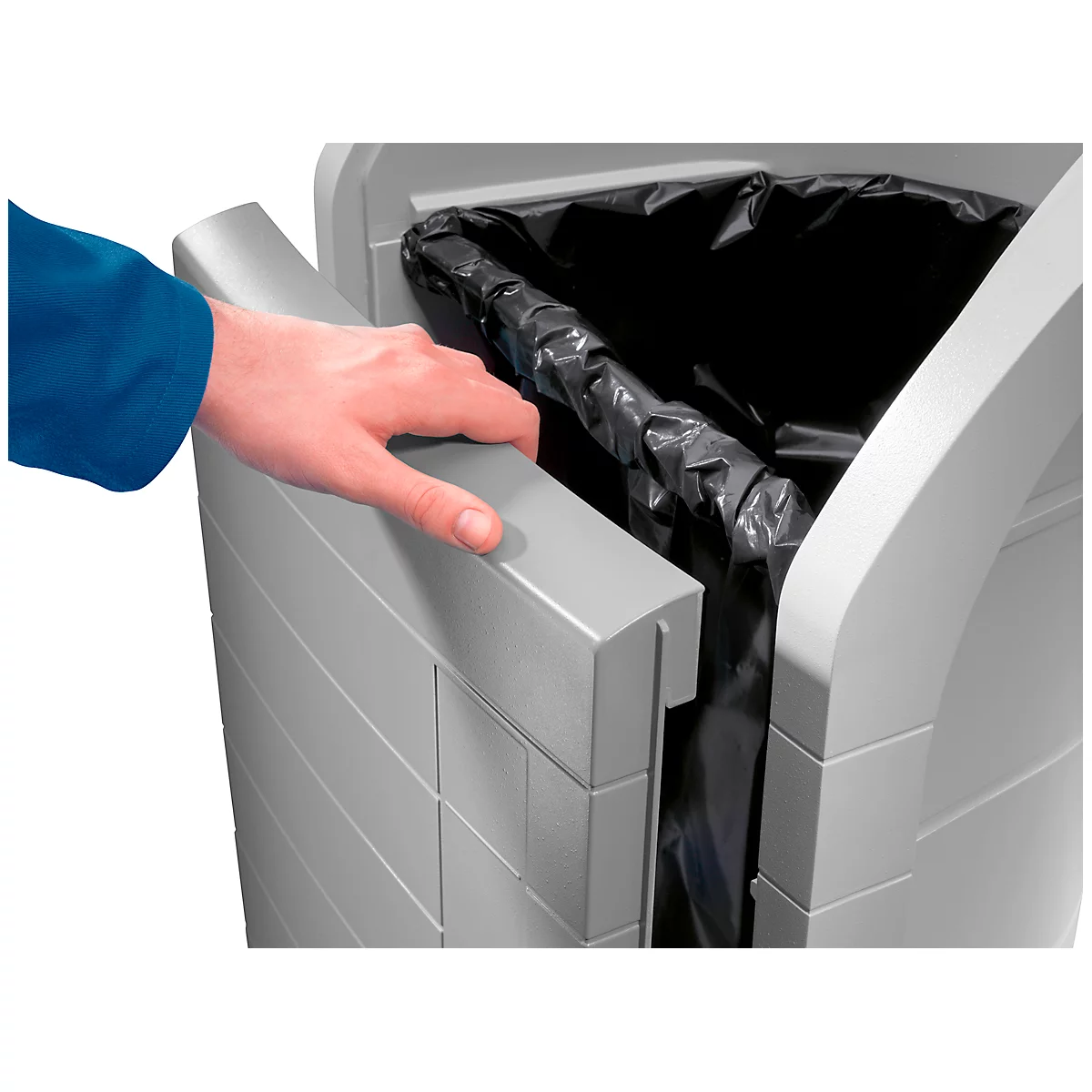 A hand holds a gray trash can lid. A black trash bag is partially visible.